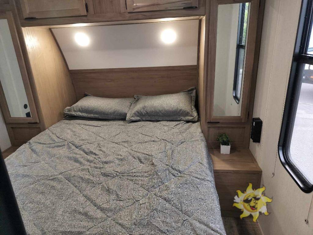 RV rental bedroom with comfortable bed, overhead lights, storage, and a window. Great for your travels!. Forest River 29QB 2024