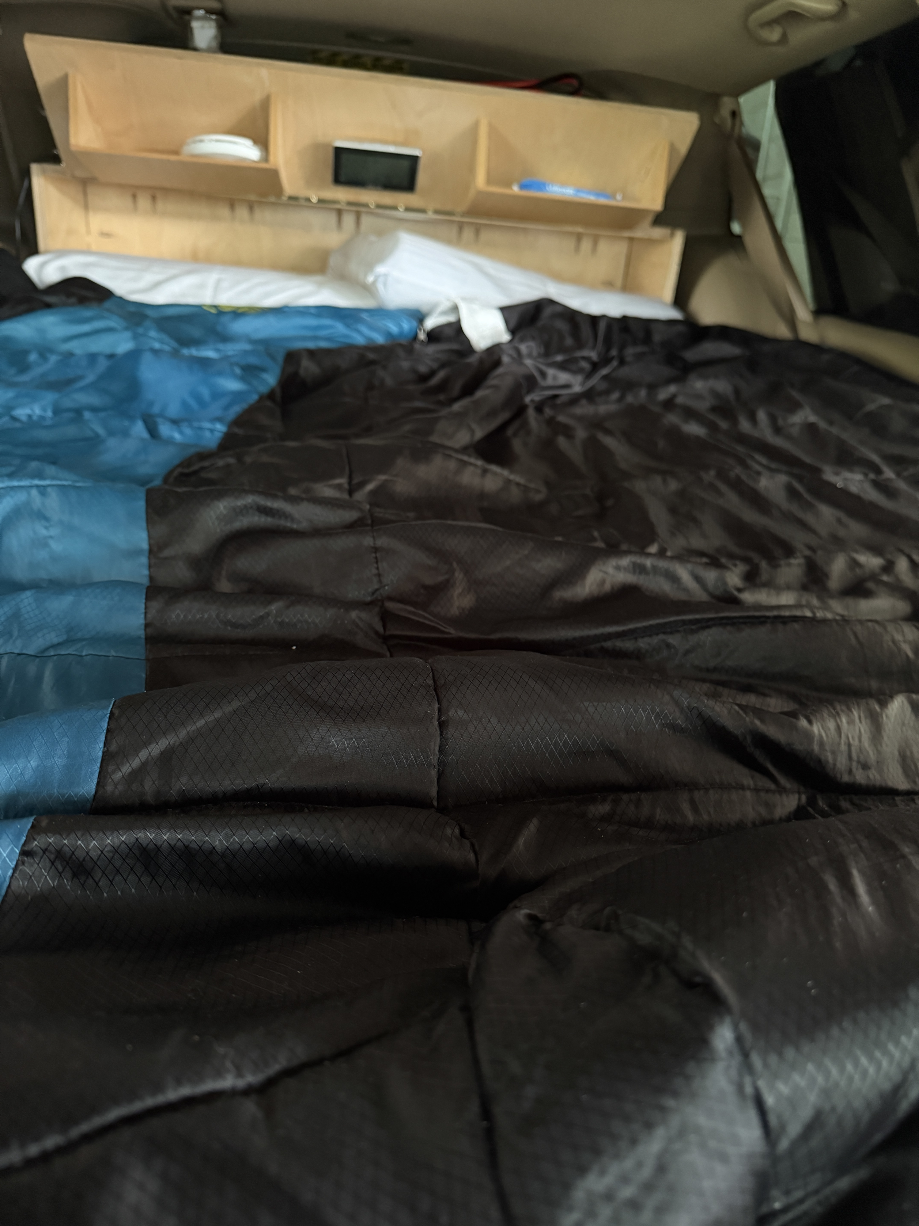 Inside a converted RV rental, a sleeping area with blue and black bedding, topped by a built-in wooden storage shelf.. Hobby Vantana 65E 2007