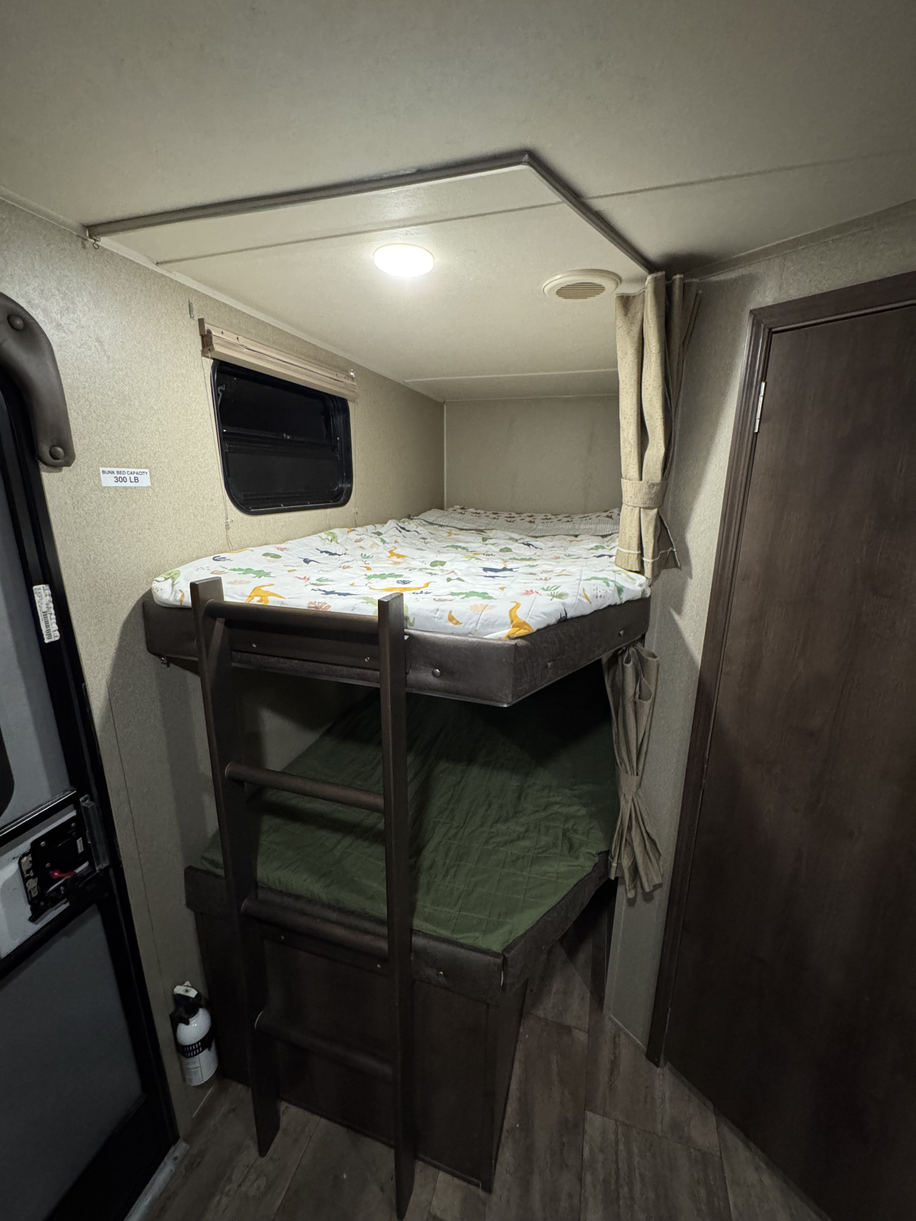 Inside an RV rental, featuring comfortable bunk beds with a ladder, window, and fire extinguisher for safe family travel.. Forest River Palomino Puma 2018