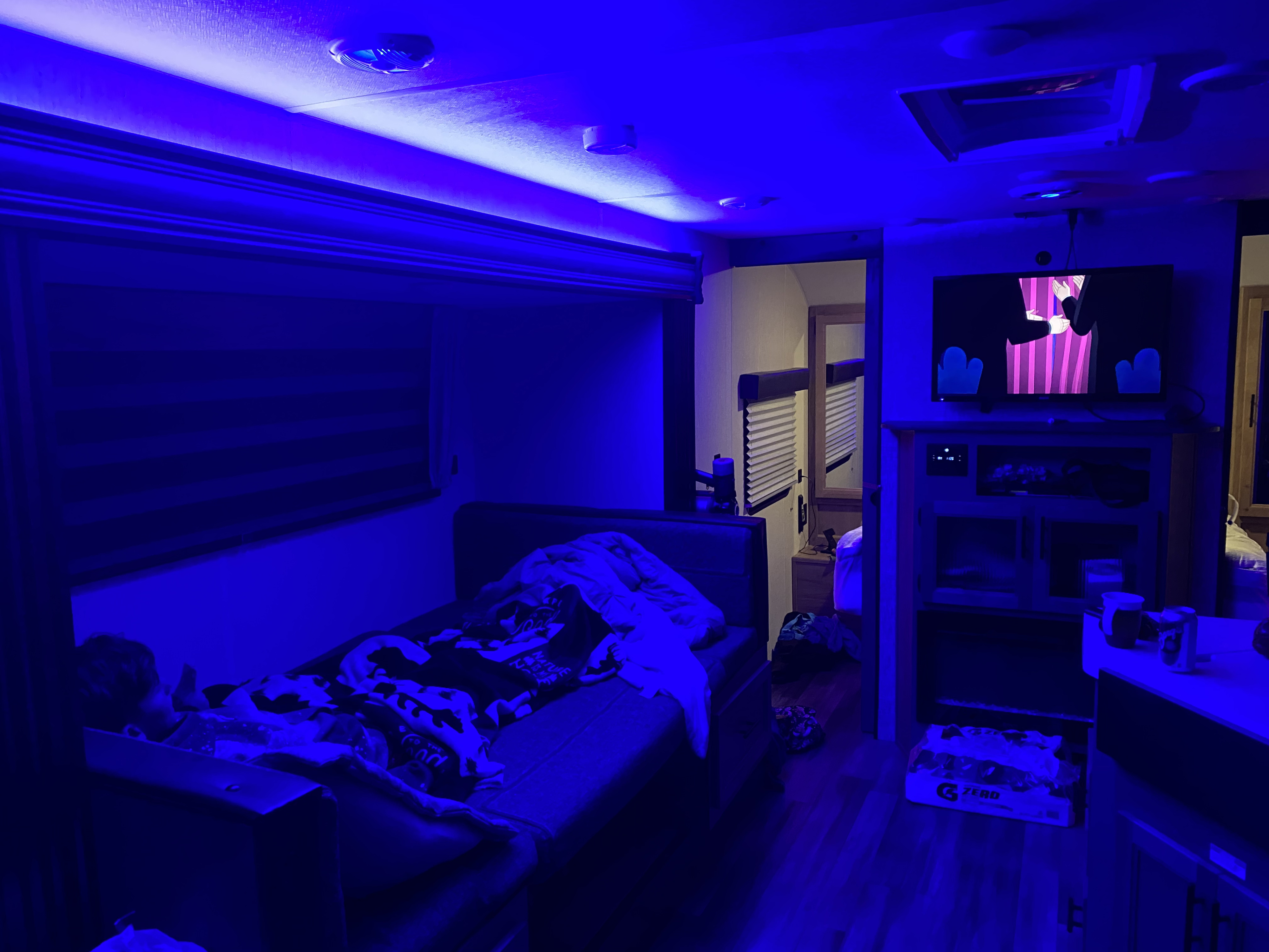 Cozy RV rental interior with blue ambient lighting, TV entertainment, and comfortable bedding for a relaxing stay.. Forest River Cherokee Grey Wolf 2023