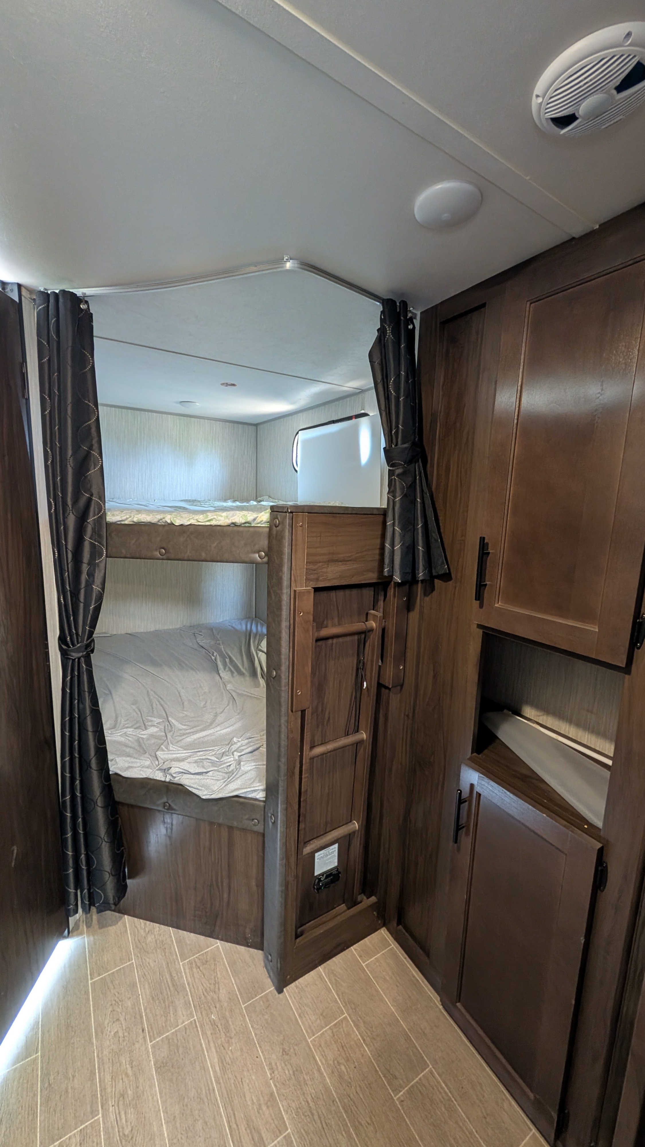 RV rental interior: A cozy bunk bed sleeping area with wood accents, a privacy curtain, and storage cabinets.. Forest River Cherokee Grey Wolf 2021