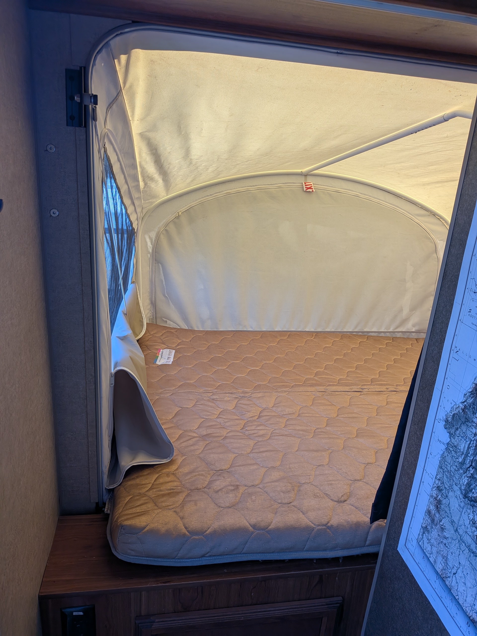 Cozy pop-up tent bed with quilted mattress in an RV rental, featuring canvas walls and a screened window.. Starcraft AR-One 2015