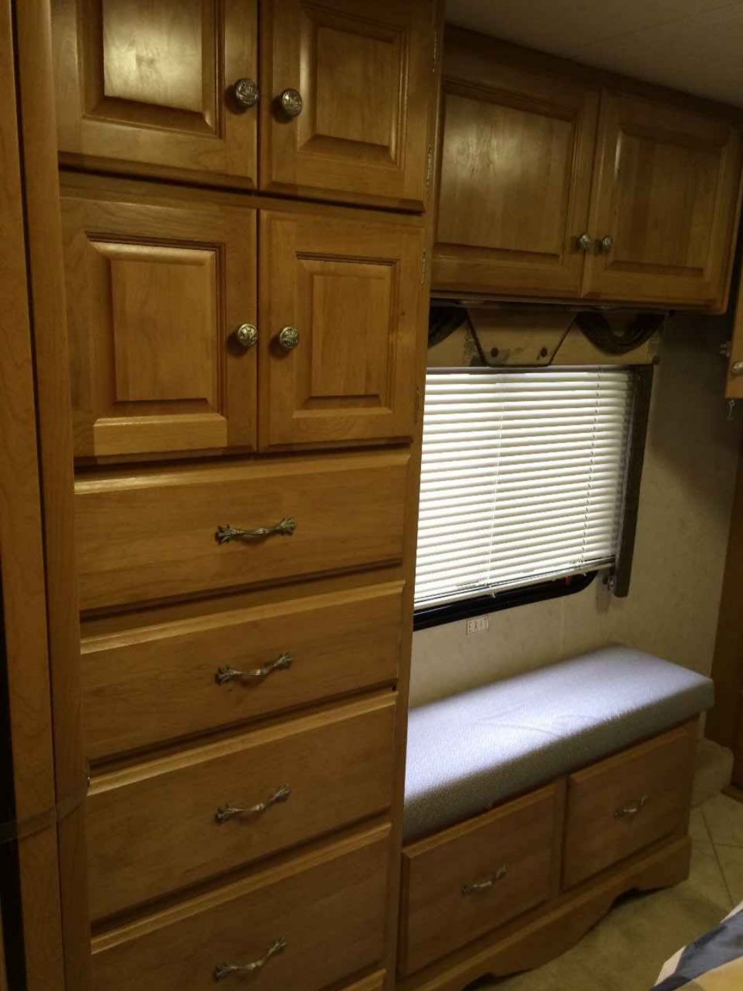 RV rental interior features wooden storage cabinets, multiple drawers, a window with blinds, and a cushioned bench.. Safari Cheetah 2005