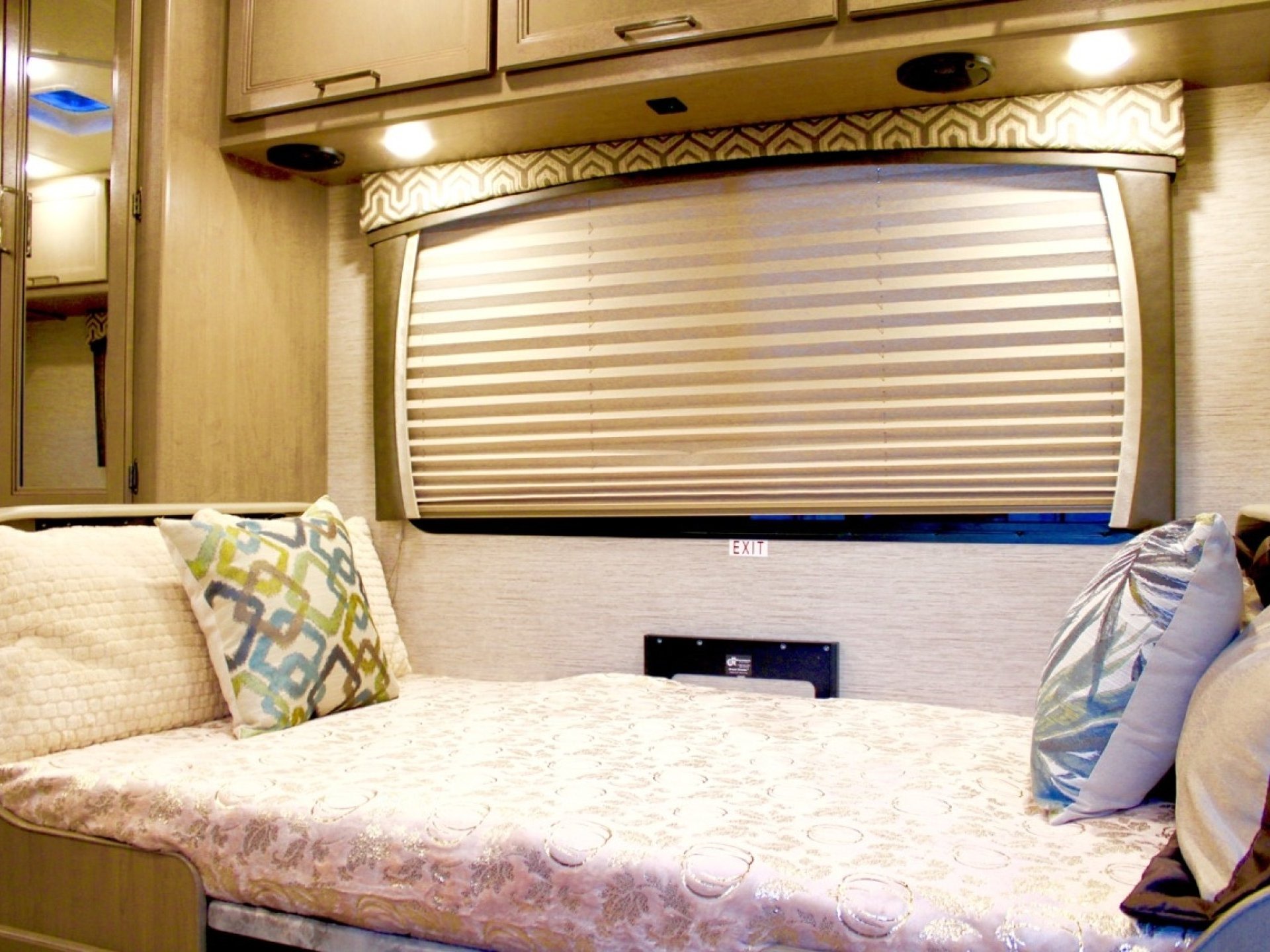 Cozy RV rental sleeping area with a comfortable bed, window blinds, and overhead storage cabinets for your travels.. Thor Chateau 2022