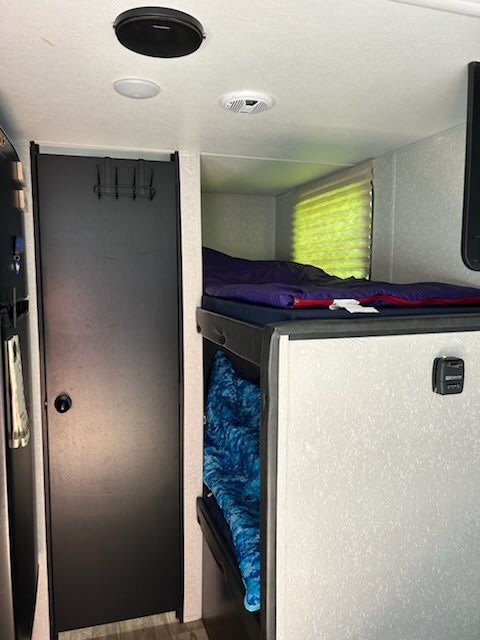 RV rental interior featuring stacked bunk beds for compact sleeping, a door, and overhead speaker/vents.. Forest River Cherokee Wolf Pup 2021