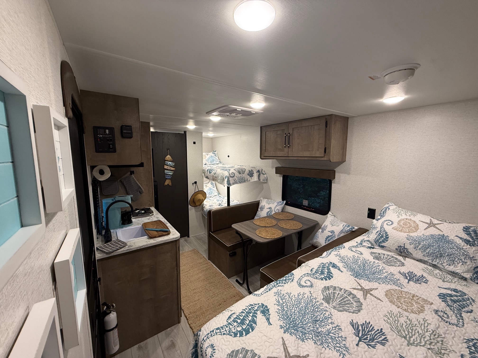RV rental interior features a coastal-themed bedroom, dining, kitchen, and convenient bunk beds, ideal for family trips.. Keystone RV Springdale 2025