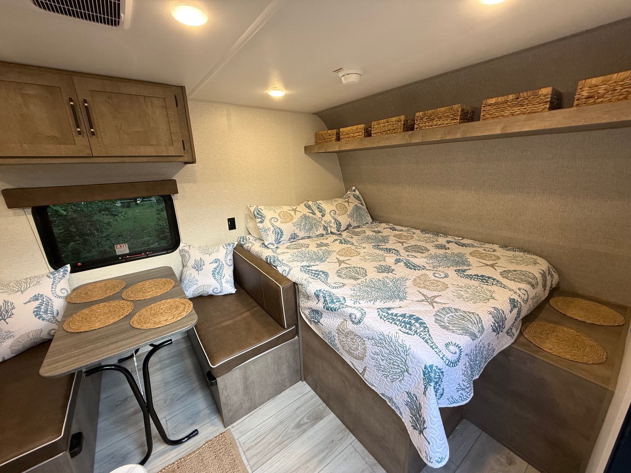 Relax in this charming rv rental: coastal-themed bed, dinette with placemats, and clever storage solutions.. Keystone RV Springdale 2025
