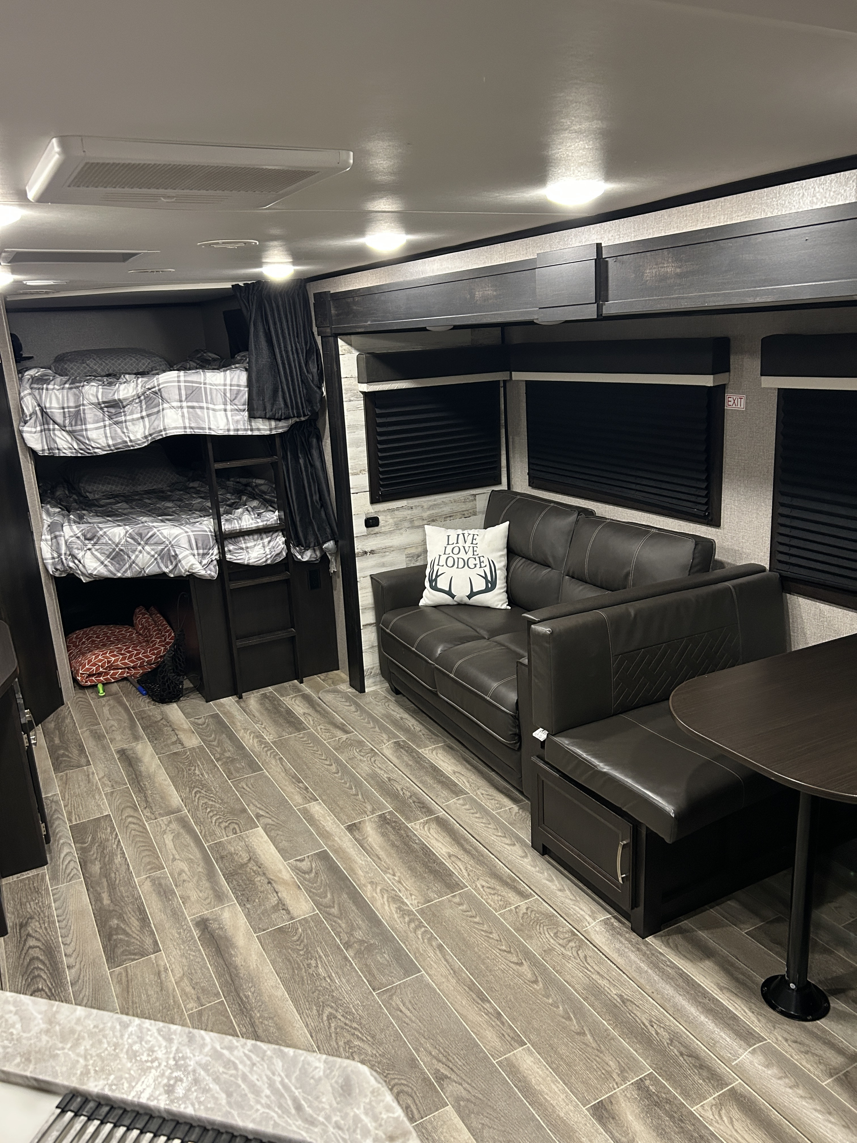 Modern RV rental interior featuring bunk beds, a comfortable sofa, and a dinette for a cozy travel experience.. Jayco Jay Feather 2021