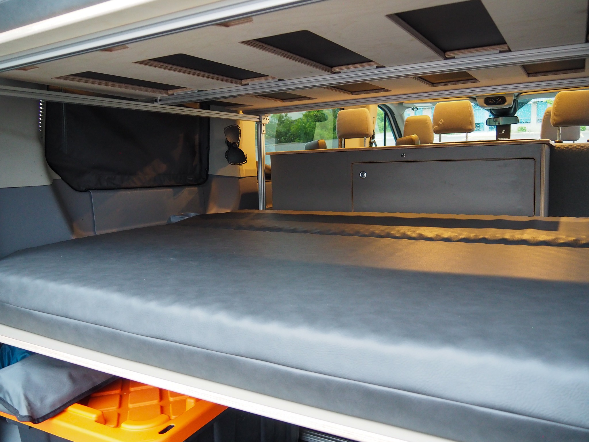 Comfortable bed, storage, and front cabin view inside this custom RV rental camper van interior for adventurers.. Ford Transit 2019