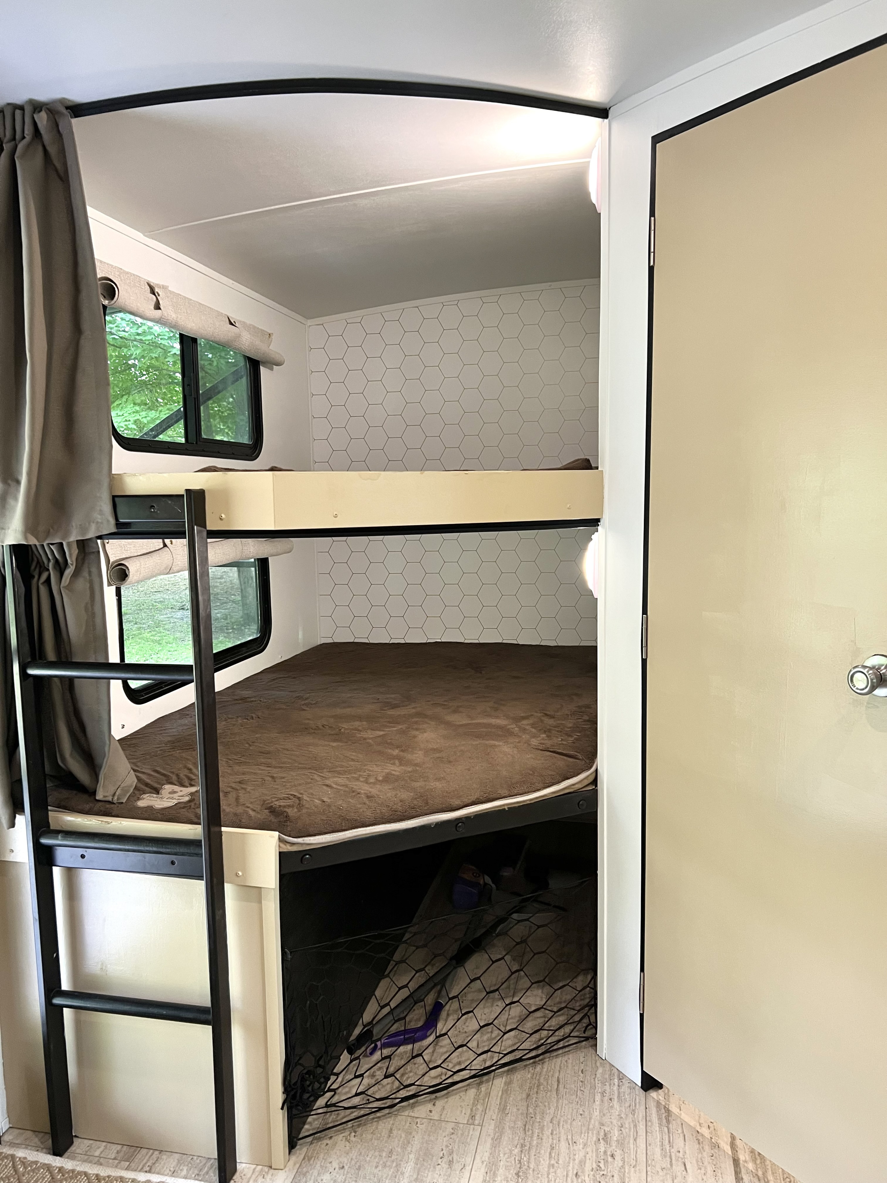 RV rental interior: Cozy bunk beds with a ladder, window views, and a storage net below, perfect for family trips.. Grand Design Imagine 2016