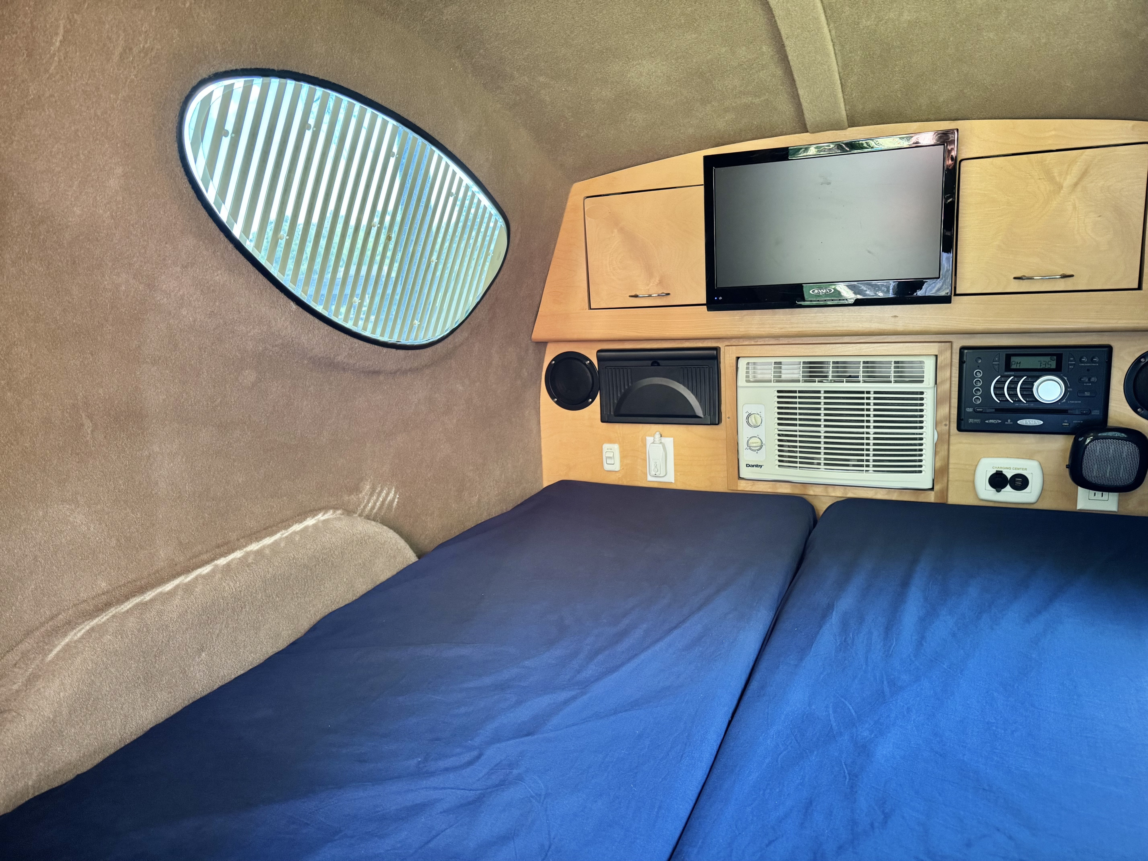 RV rental interior: two beds with blue sheets, a Jensen TV, Danby AC, and stereo system. Cozy space for travel.. Little Guy MyPod 2017