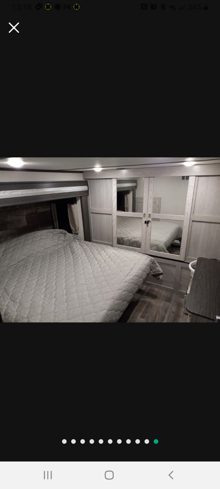 RV rental bedroom: light gray quilted bed, mirrored closet reflecting the bed, and wood-look flooring.. Keystone RV Montana High Country 2021