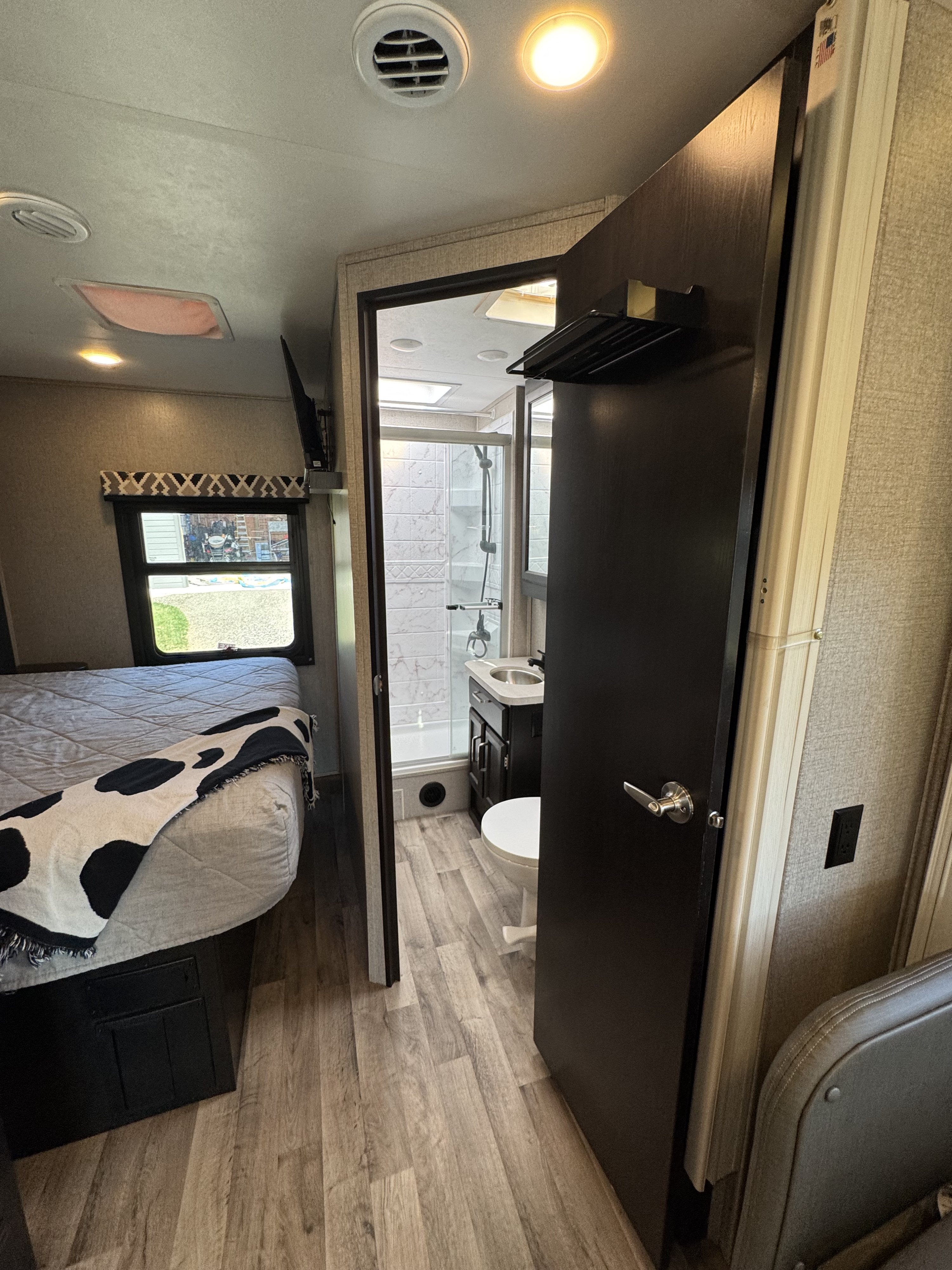 Cozy RV rental interior featuring a bedroom with a bed & TV, plus an attached bathroom with a shower, sink, and toilet.. Entegra Coach Odyssey 2021