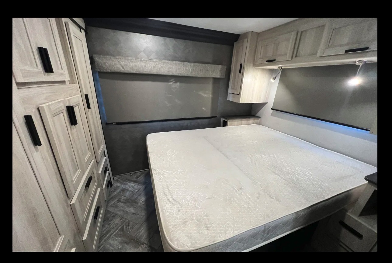 This RV rental bedroom offers a comfortable bed, light wood cabinets, and storage, ideal for your next trip.. Forest River Sunseeker 2021