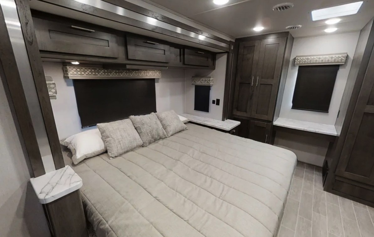 Spacious and modern RV rental bedroom with a large bed, overhead cabinets, and built-in storage, offering comfort for your travels.. Forest River gt5 2021