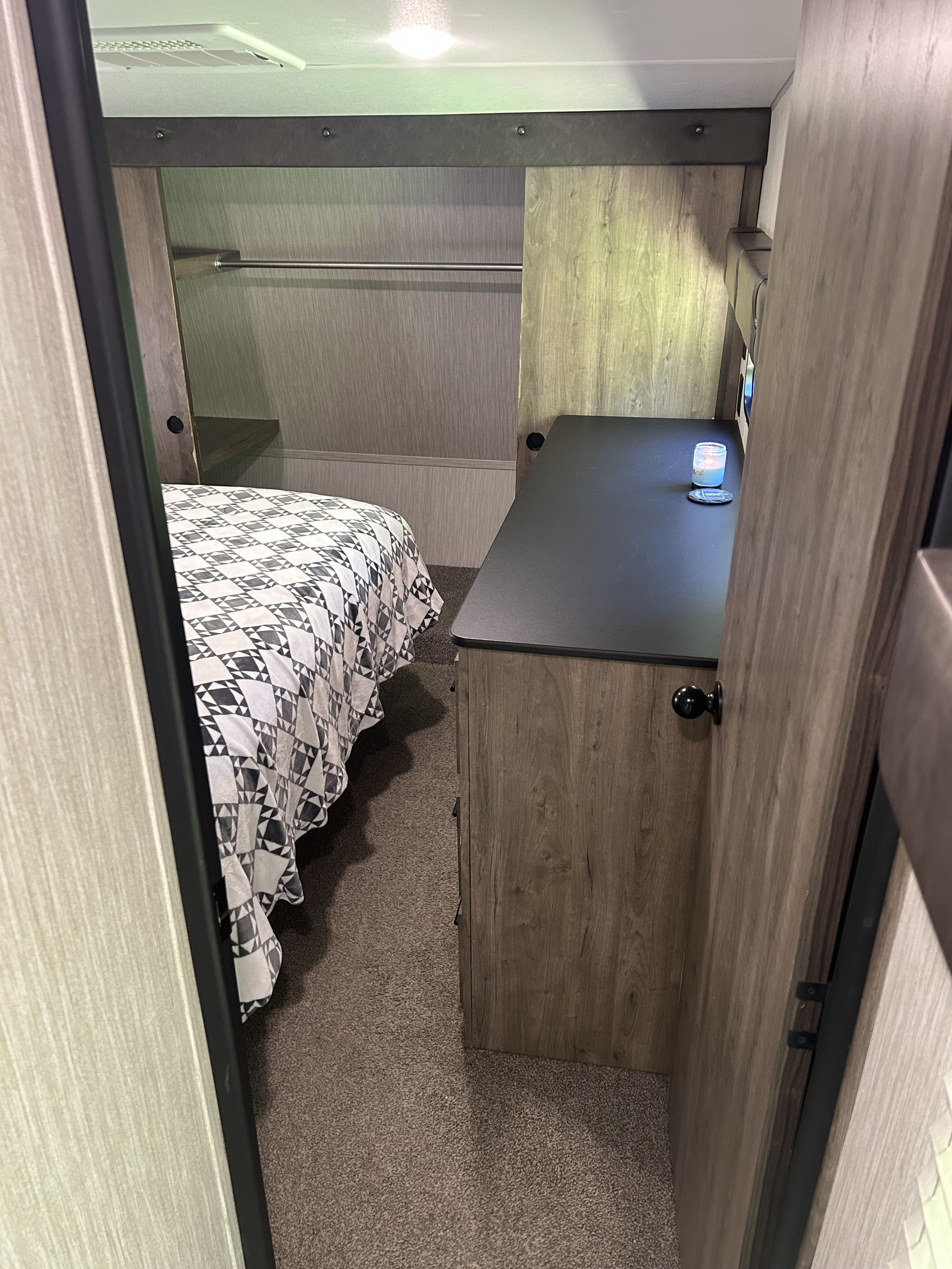 View inside an RV rental bedroom showing a bed, dark wood-grain dresser, and built-in closet storage.. Forest River Vengeance 2020