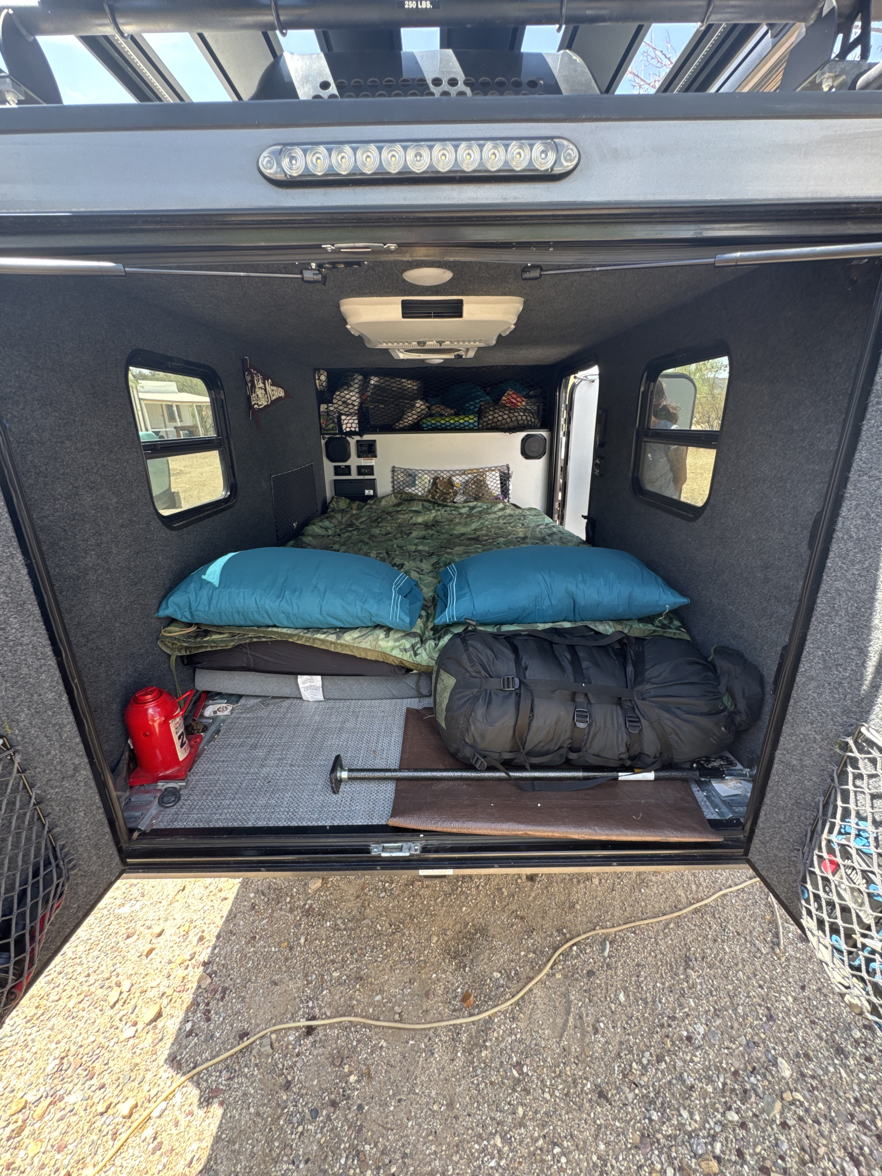 Cozy RV rental: interior with bed, overhead AC, and organized gear for camping trips.. InTech RV Flyer 2022