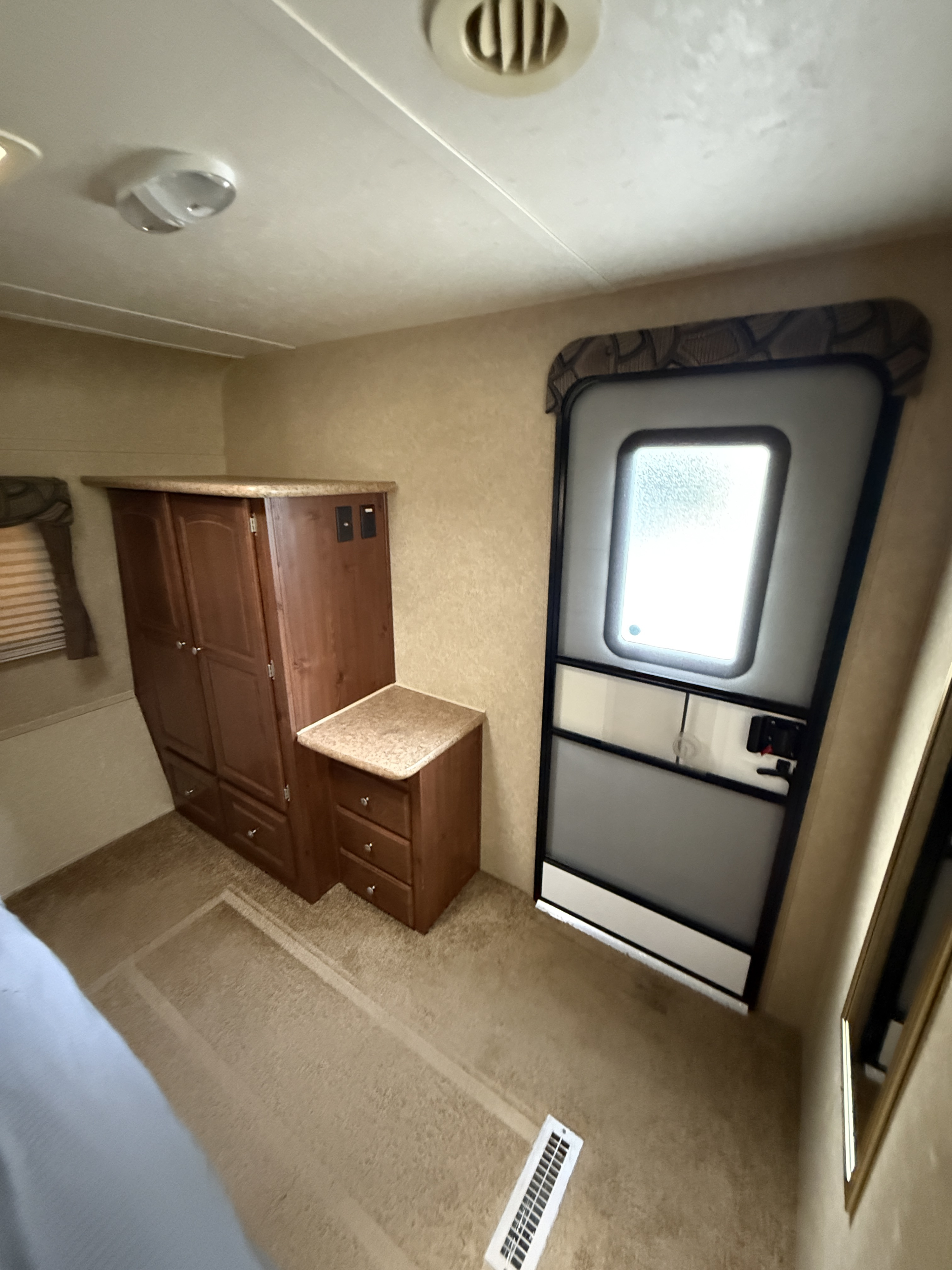 Cozy interior of an RV rental, featuring wood cabinets, a door, and carpeted floor, offering comfortable living space.. Rockwood Signature Ultra Lite 2012
