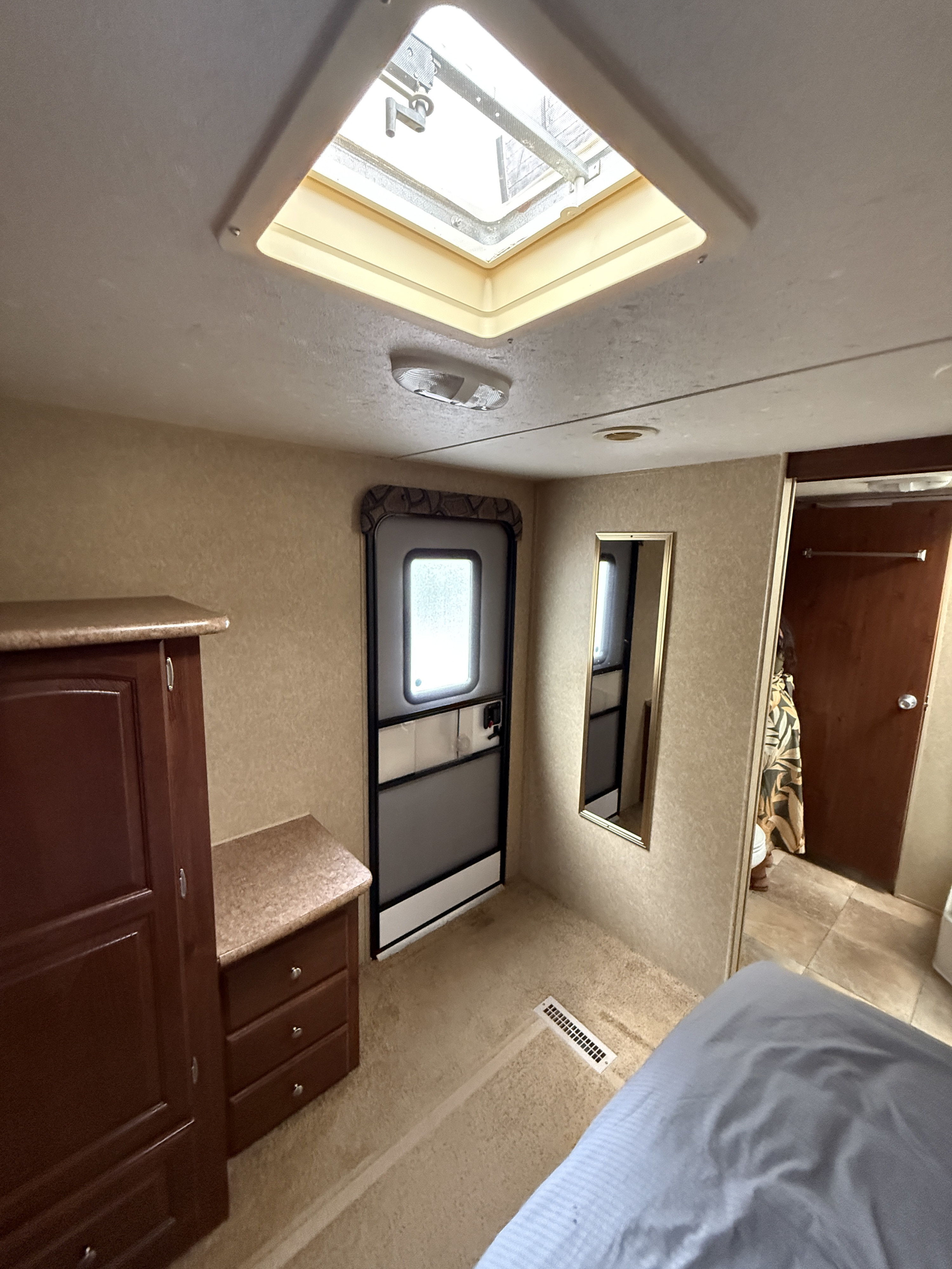 RV rental bedroom view: Features a bright skylight, wood cabinets, entry door, and wall mirror.. Rockwood Signature Ultra Lite 2012
