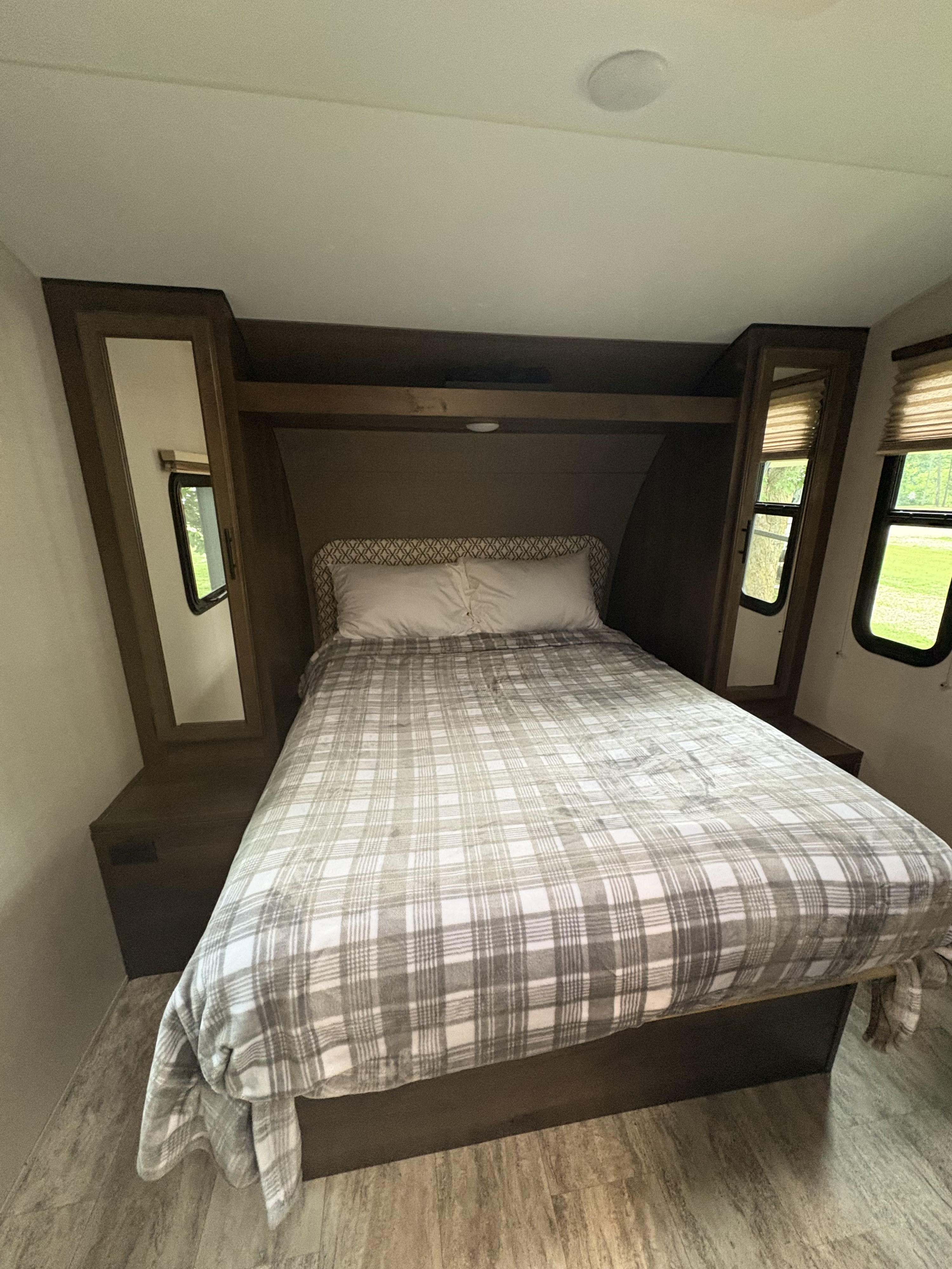 Inside an RV rental: a compact bedroom with a comfy plaid bed, side cabinets with mirrors, and natural light from windows.. KZ Connect 2018