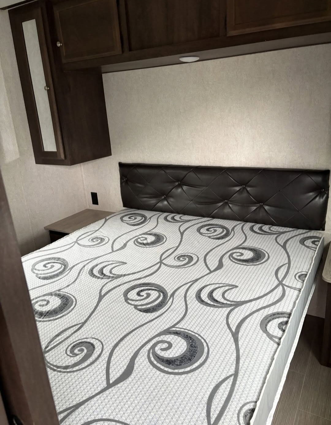 RV rental bedroom: comfortable bed with a unique grey pattern, tufted headboard, and overhead storage.. Starcraft GPS 2018