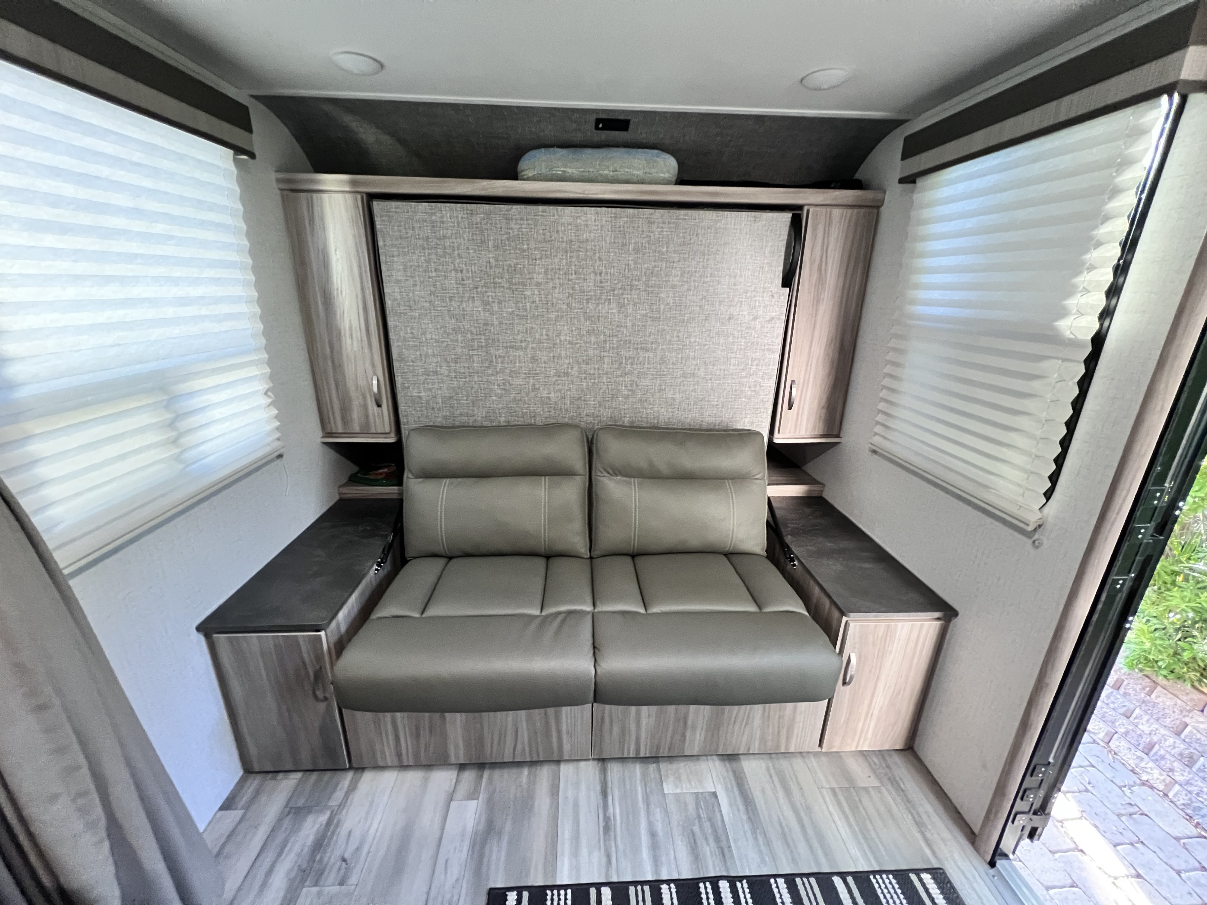 This RV rental's compact living space features a gray convertible sofa/bed, side storage, and windows with blinds. Modern and functional.. Winnebago Micro Minnie Flx 2022