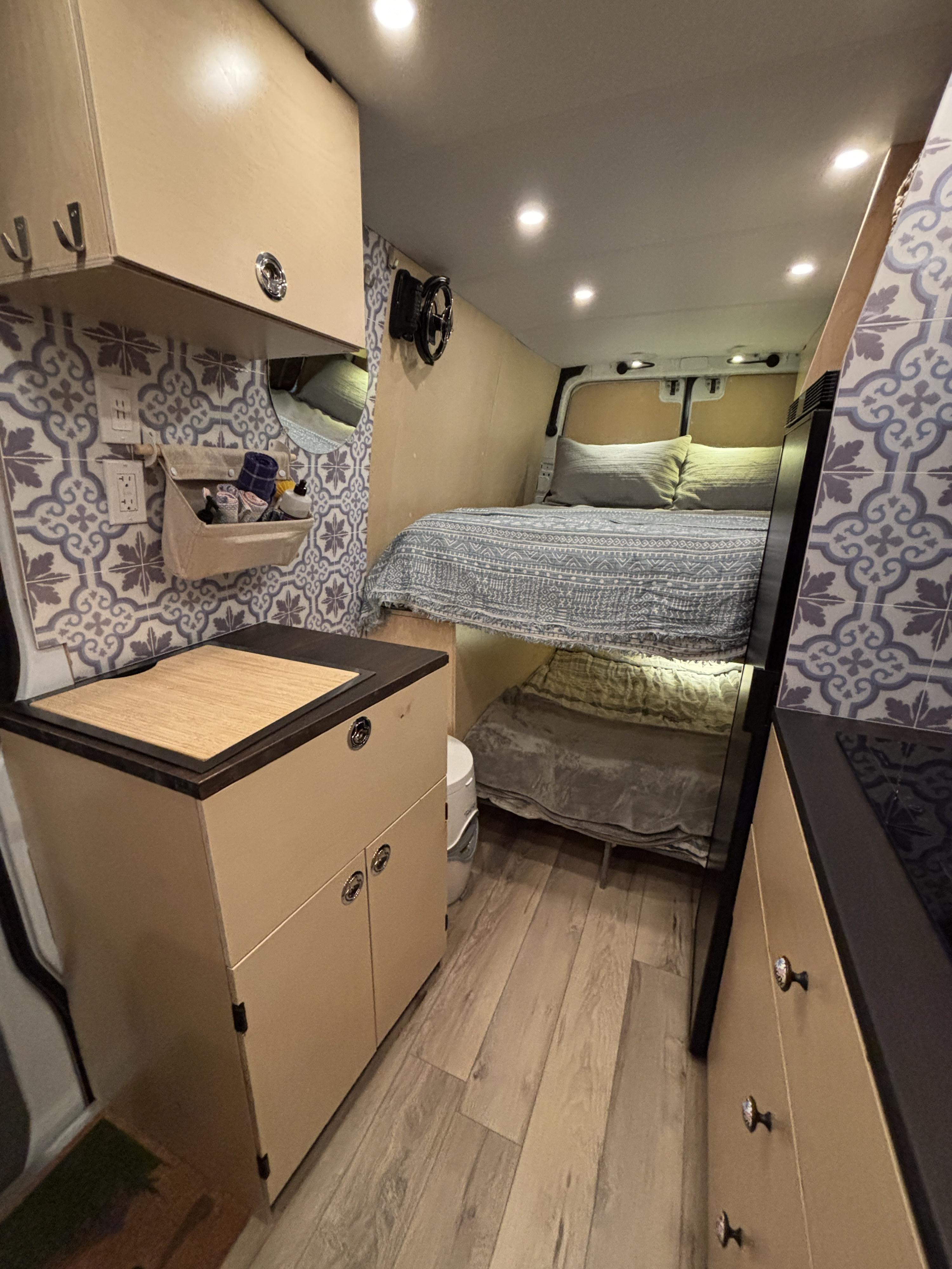 Cozy RV rental interior with compact kitchen, patterned backsplash, and bunk beds. Efficient use of space for mobile living.. Mercedes-Benz Sprinter 2013