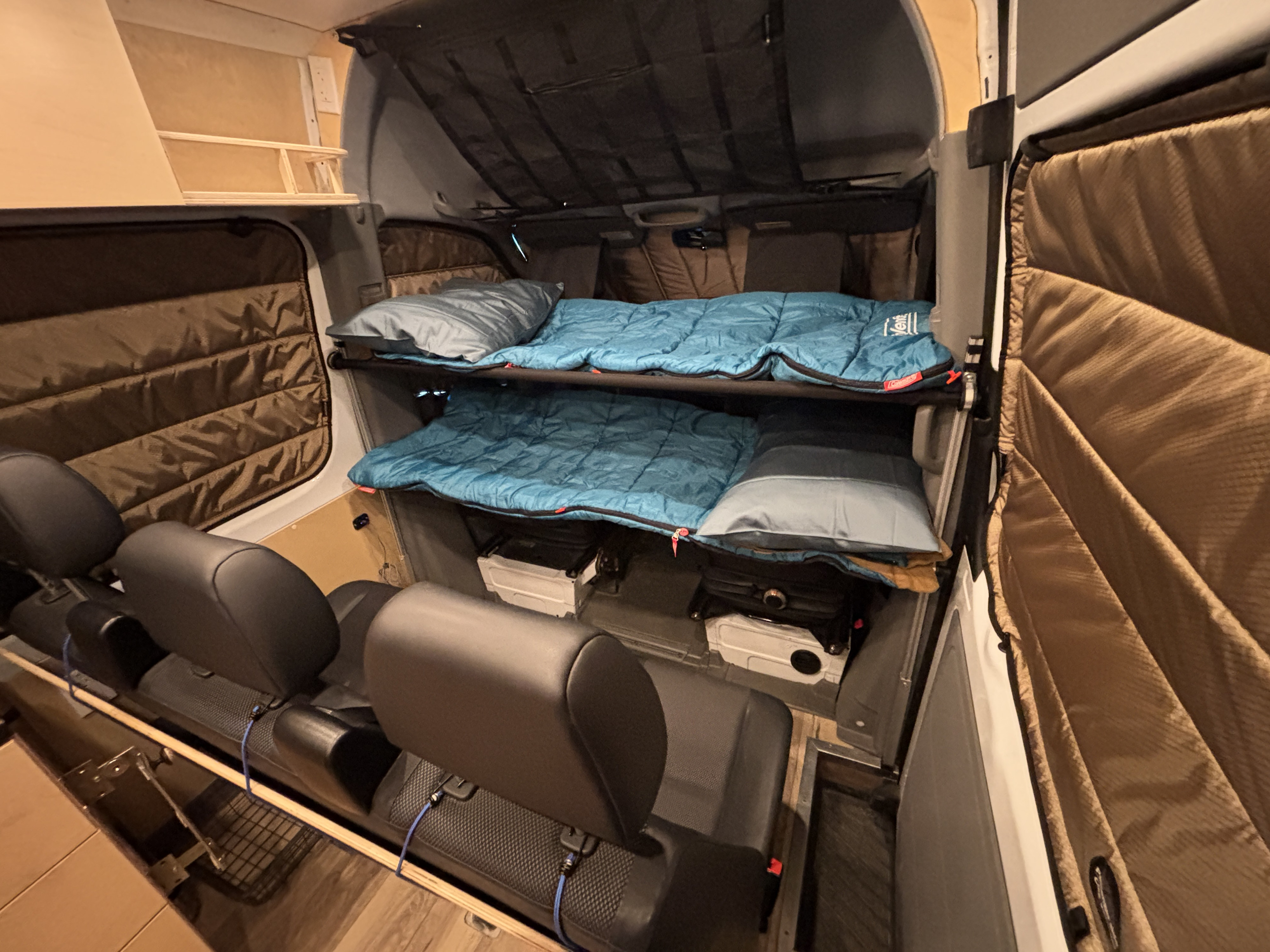 RV rental interior shows a cozy camper setup with two bunk beds, sleeping bags, storage below, and seating.. Mercedes-Benz Sprinter 2013