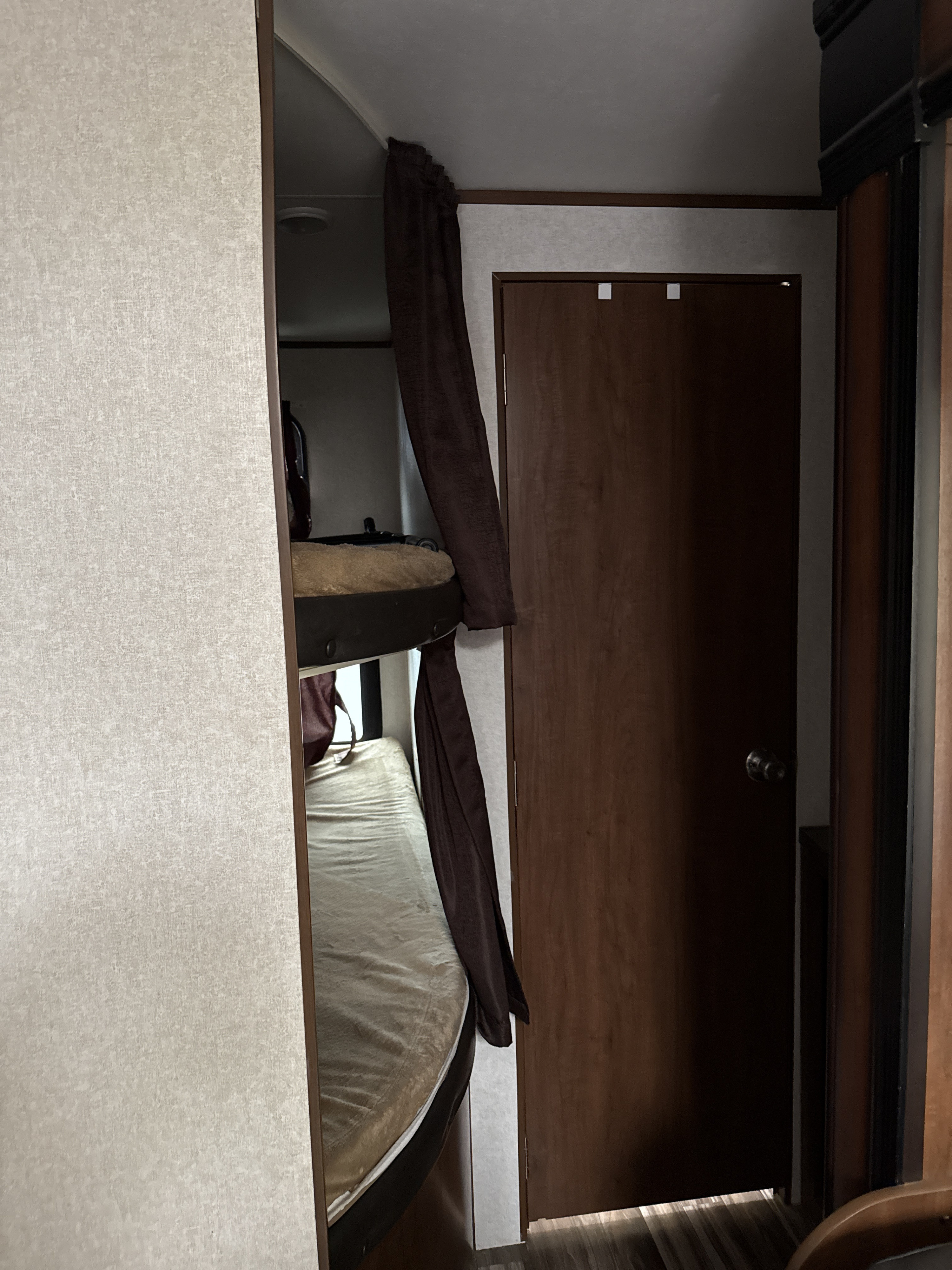 RV rental interior featuring bunk beds with privacy curtains next to a wooden door.. Jayco Jay Flight 2017