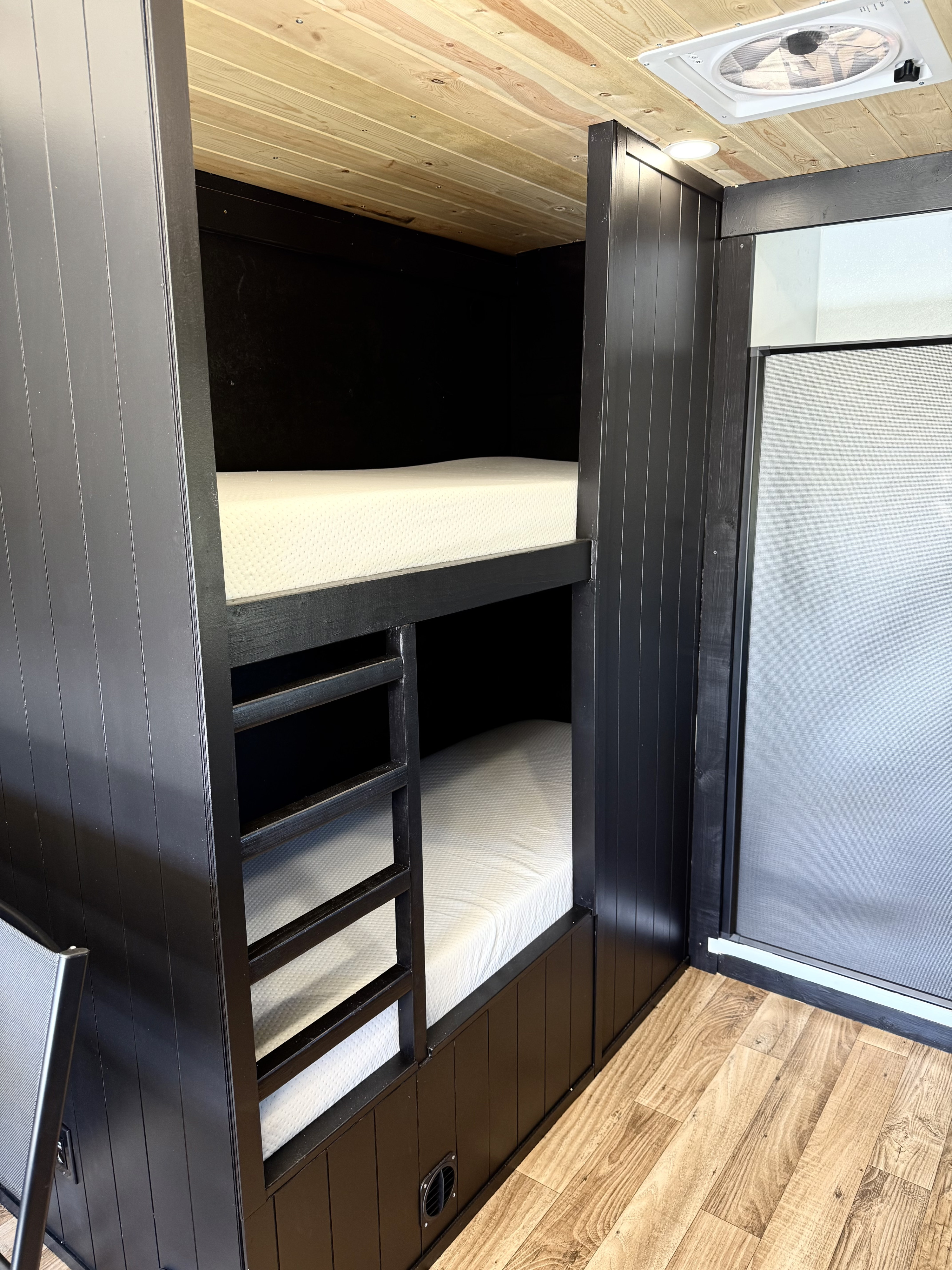 RV rental: Cozy camper interior featuring custom black bunk beds with white mattresses, light wood plank ceiling & floor.. Idaho adventure vehicles Toy hauler 20 2025
