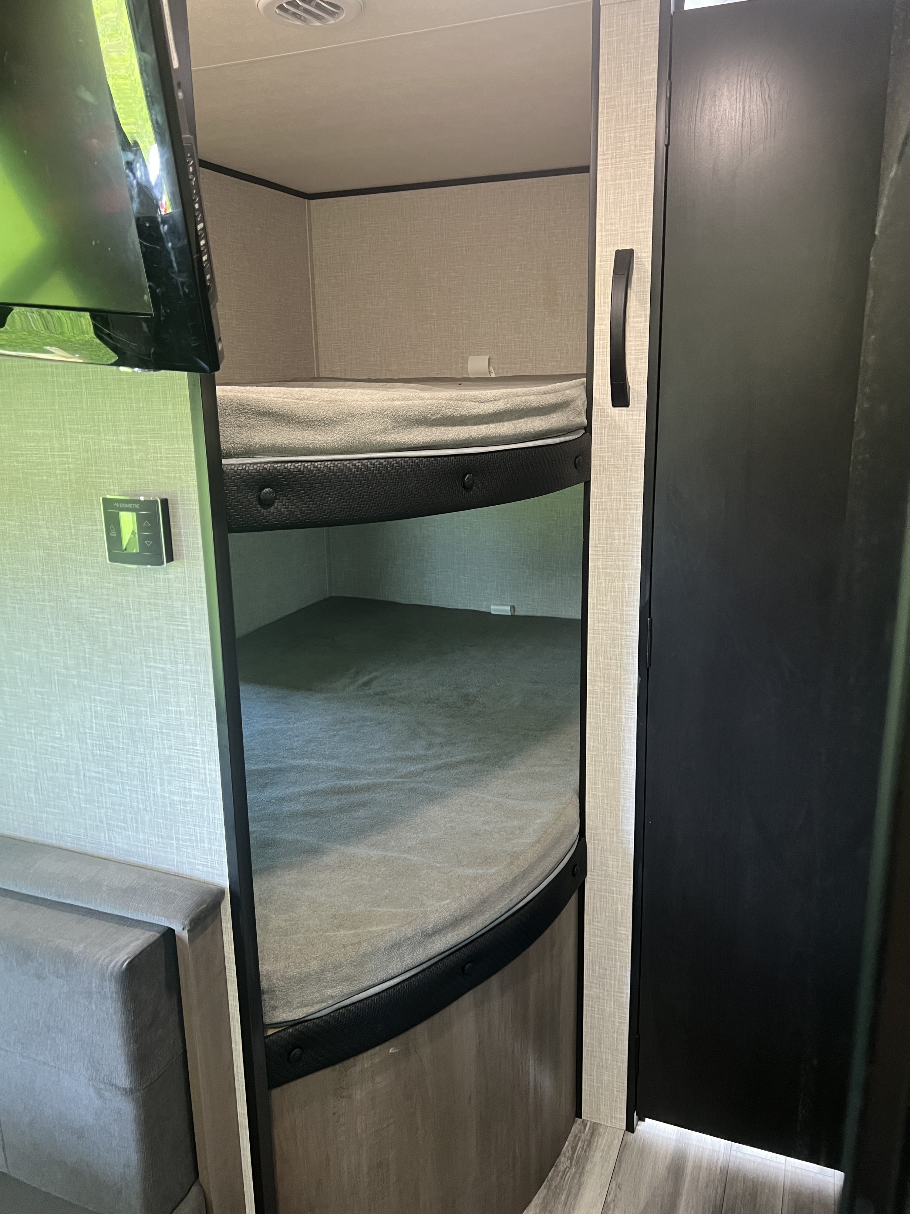 Interior of an RV rental featuring two comfortable bunk beds, a wall-mounted TV, and an interior door.. Jayco Jay Flight SLX 260BH 2025