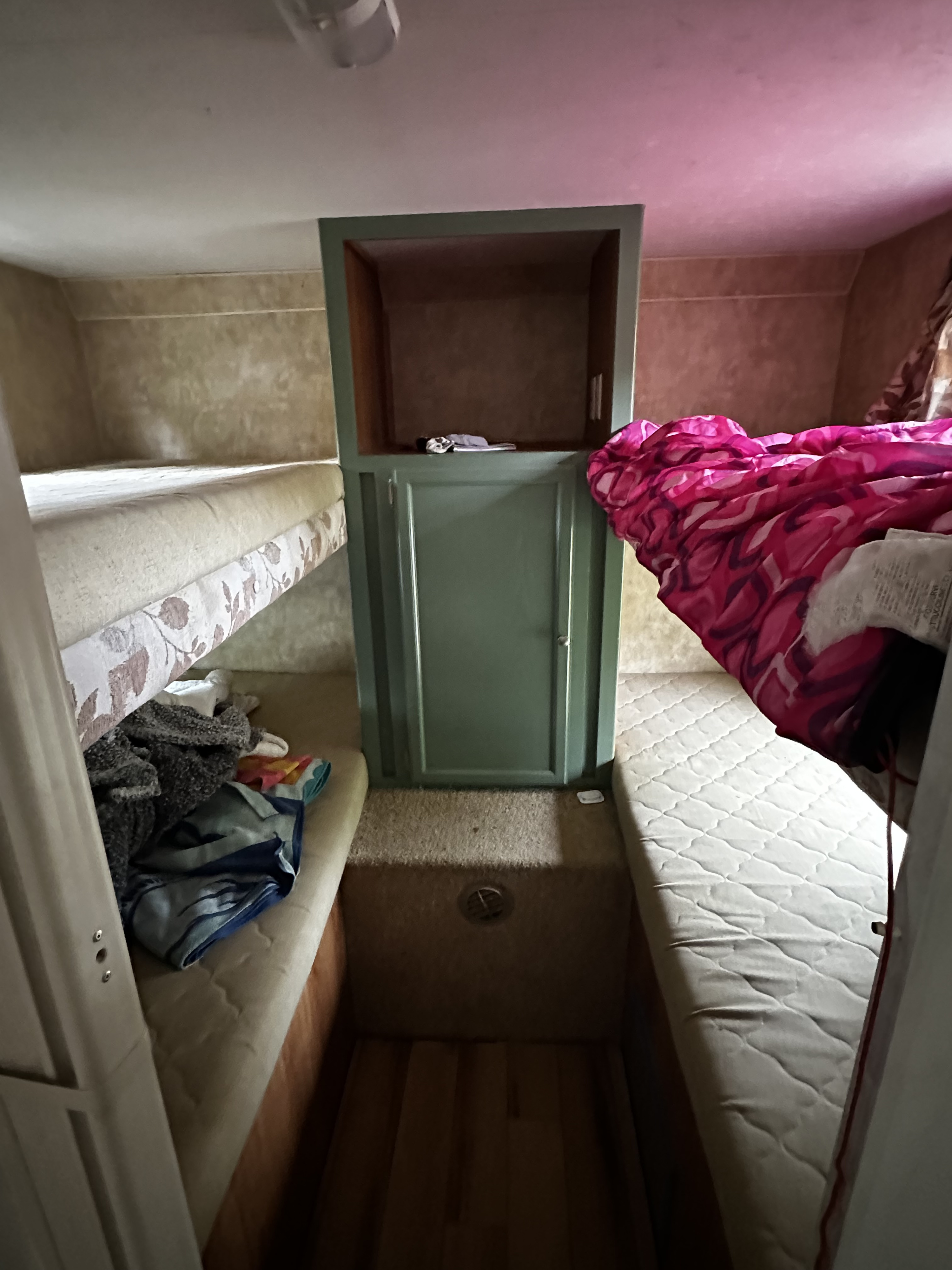 Experience the practical interior of this RV rental, featuring bunk beds, a main bed with a vibrant blanket, and a central cabinet.. Jayco Jay Flight 2008