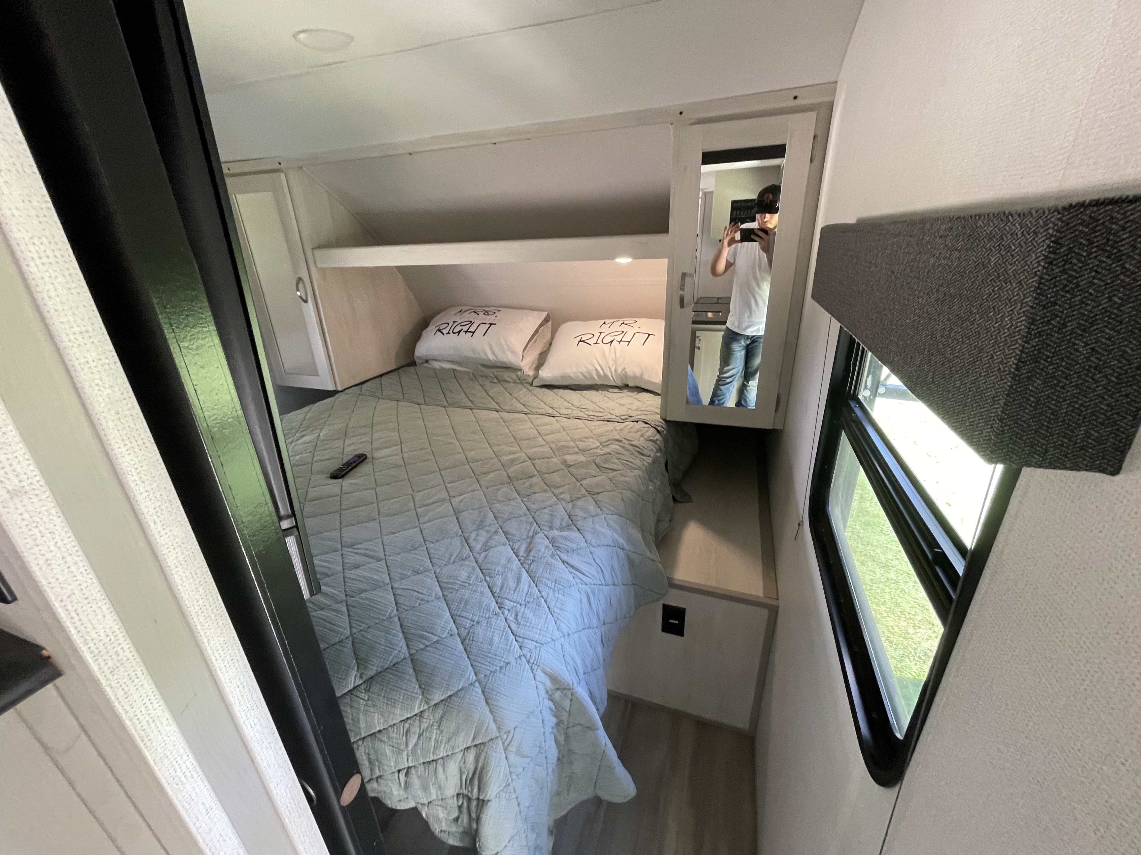 Cozy RV rental bedroom with "Mr. & Mrs. Right" pillows, mirror, and window. Ideal for compact travel.. Forest River Tracer 2021