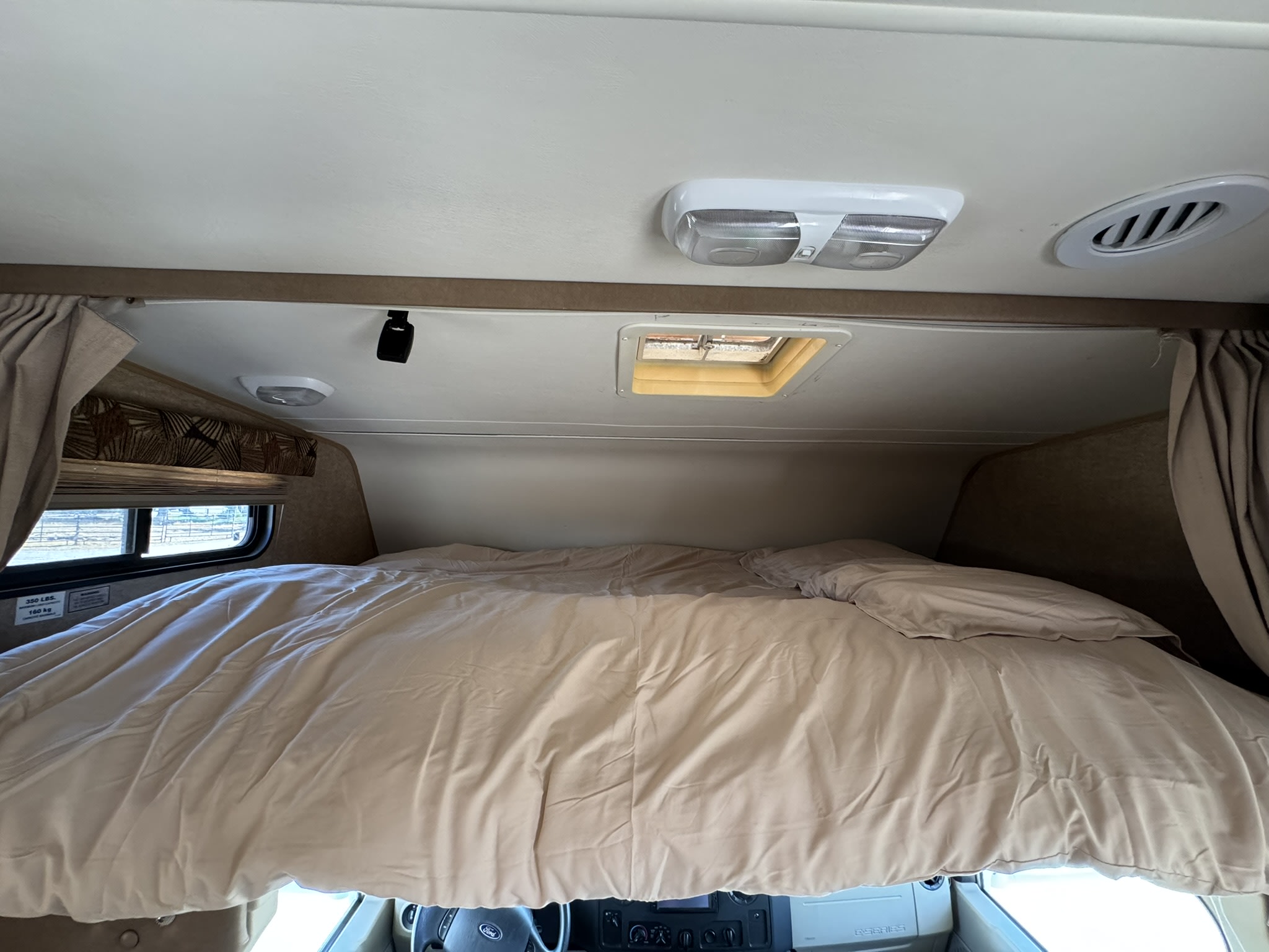 Comfortable RV rental bed above the cab, featuring a skylight, lights, and AC vent. Perfect for a cozy night's sleep.. Forest River Coachmen Leprechaun 2015