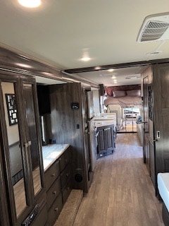Step inside this modern RV rental: a long interior with dark wood cabinets, light floors, and a bed at the far end.. Flair-Fleetwood Flair-Fleetwood Motorhome 2020