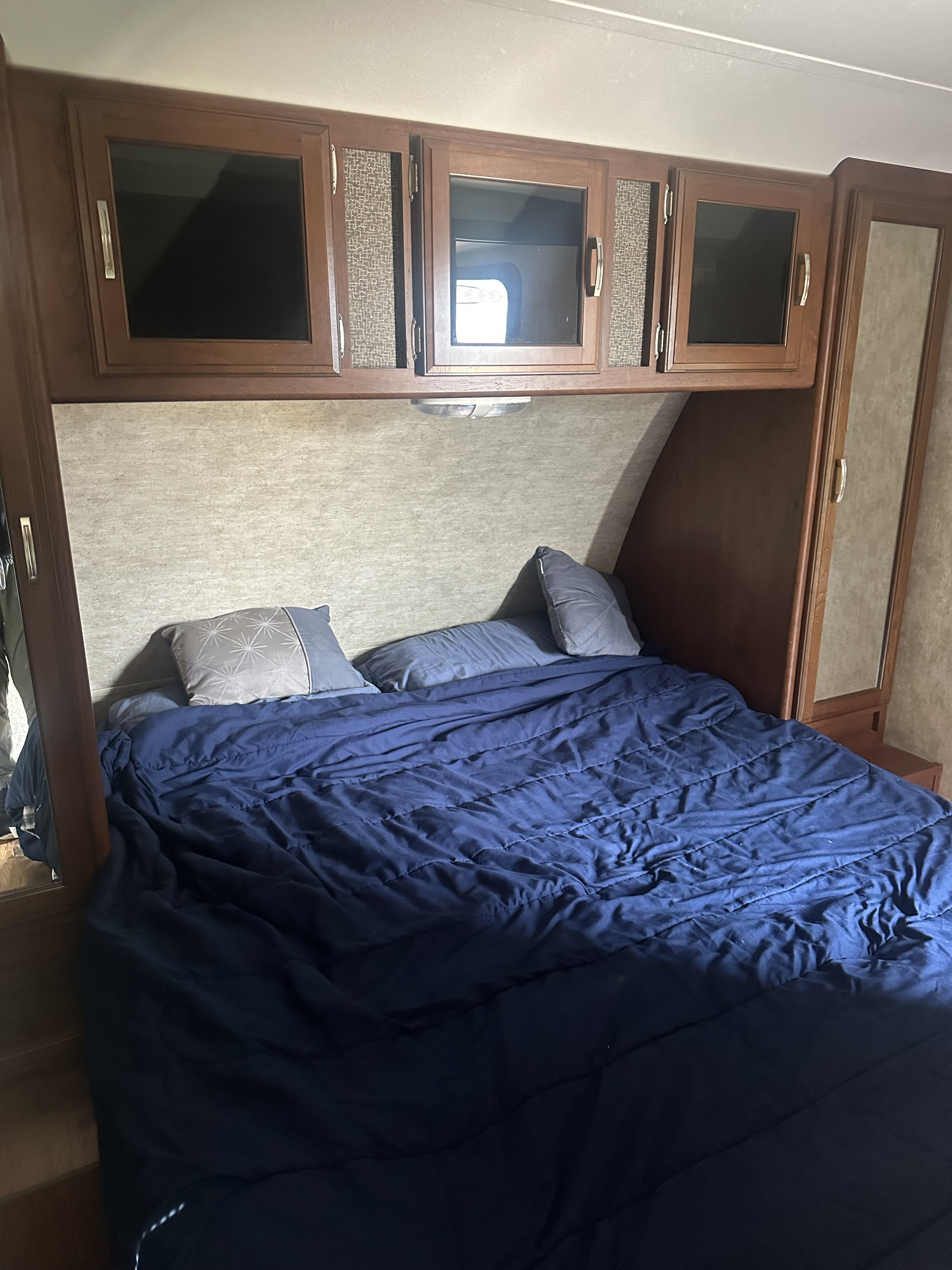 RV rental bedroom: Features a comfy bed, overhead storage, and mirrored wardrobe for compact living.. Keystone RV Passport Ultra Lite 2015
