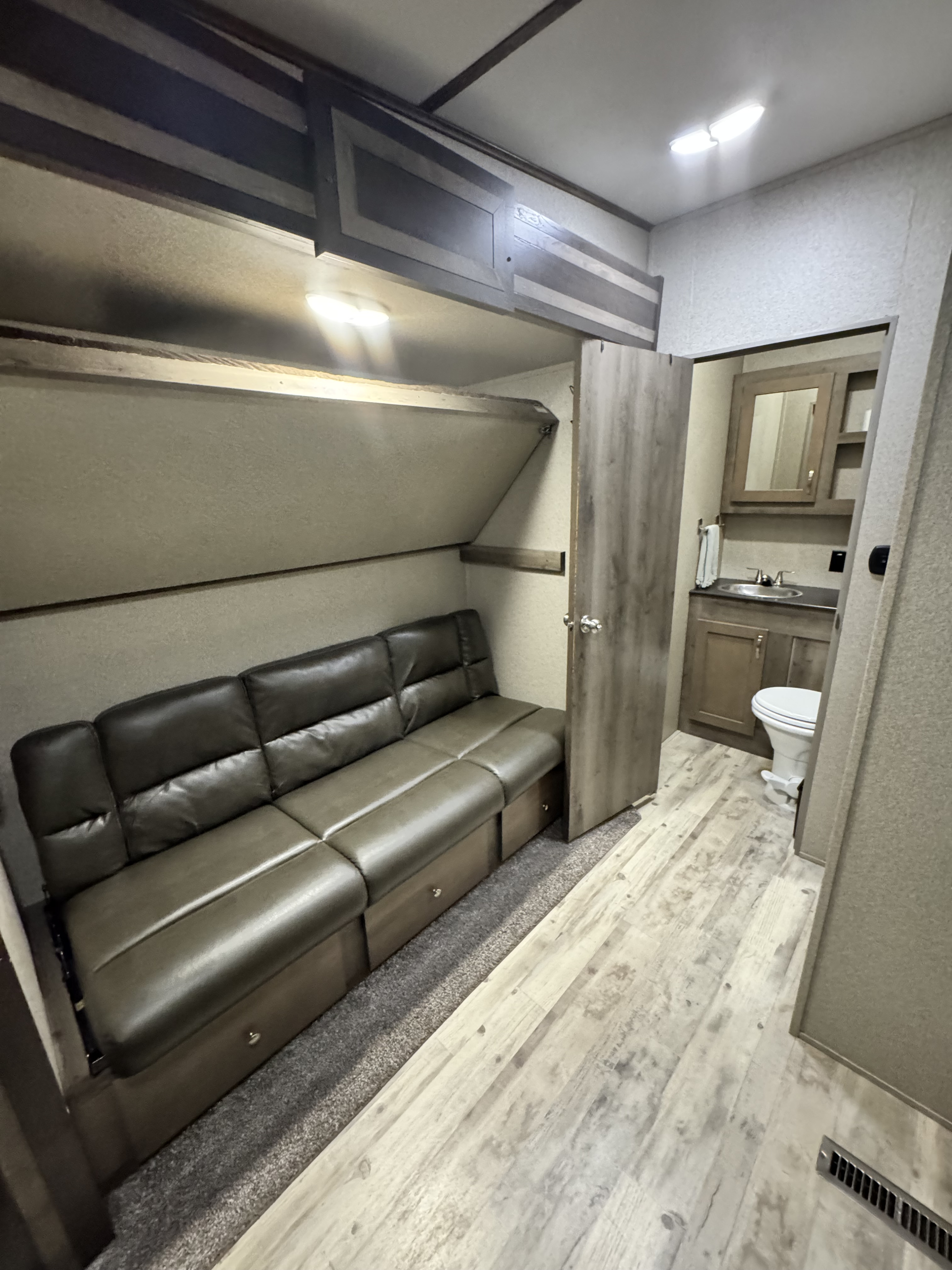 RV rental interior: features a convertible sofa, upper bunk bed, and view into the compact bathroom, ideal for travel.. Keystone RV Sprinter Campfire Edition 2020