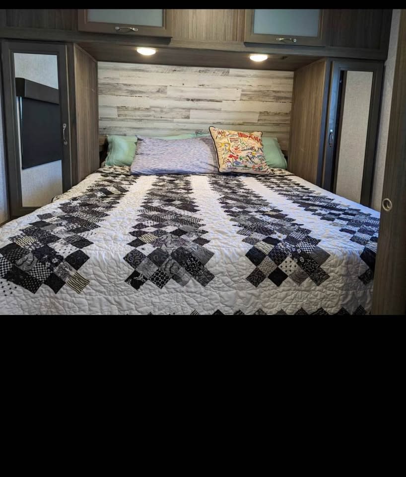 Cozy RV rental bedroom with a striking black and white quilt and built-in storage. Ideal for travel.. Dutchmen Kodiak Ultra Lite 2021
