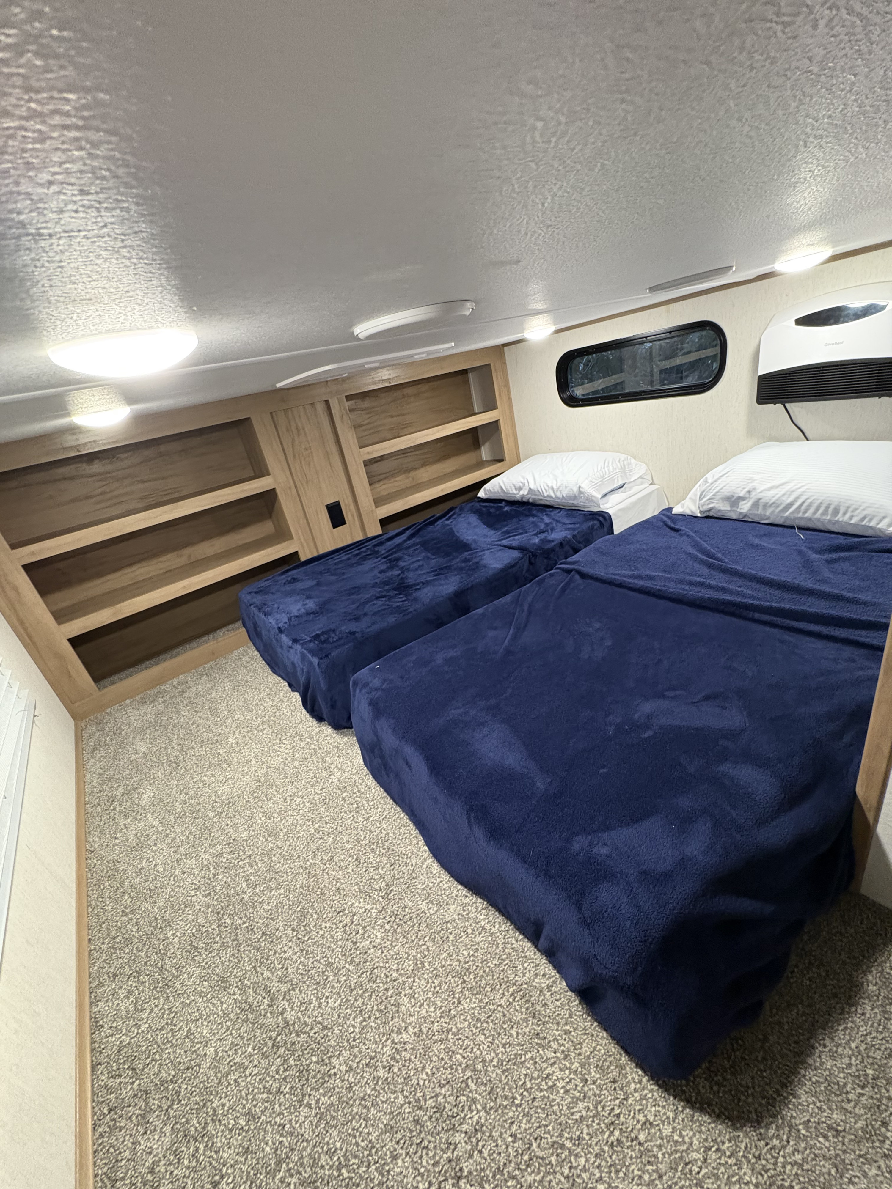 RV rental bunkhouse: Two comfortable beds with navy blankets, built-in shelves, and bright lighting.. Forest River Sabre 2023