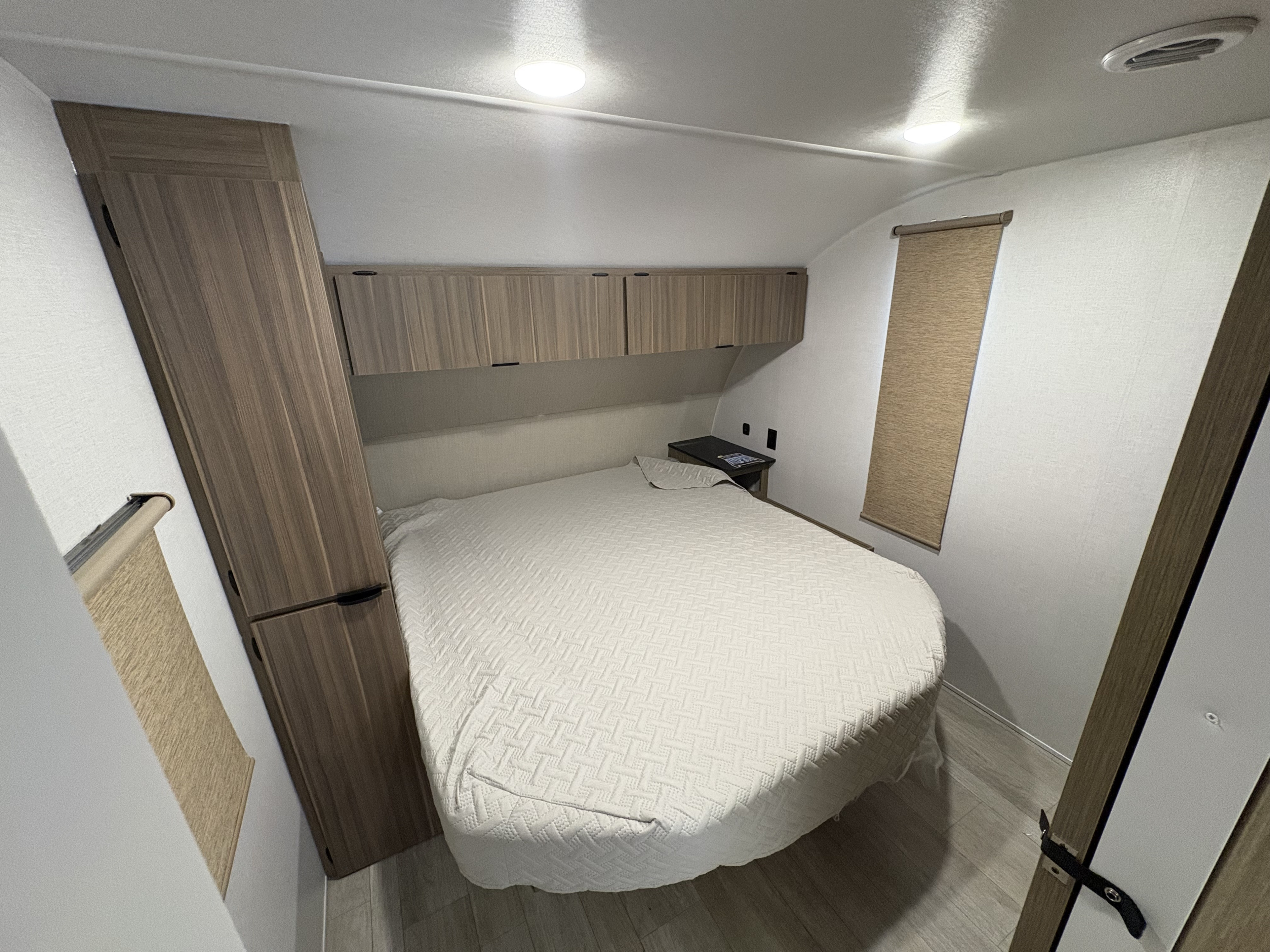 Well-lit RV rental bedroom with a large bed, light-colored bedding, overhead storage cabinets, and a tall wardrobe.. Forest River Salem Cruise Lite 26ICE 2025