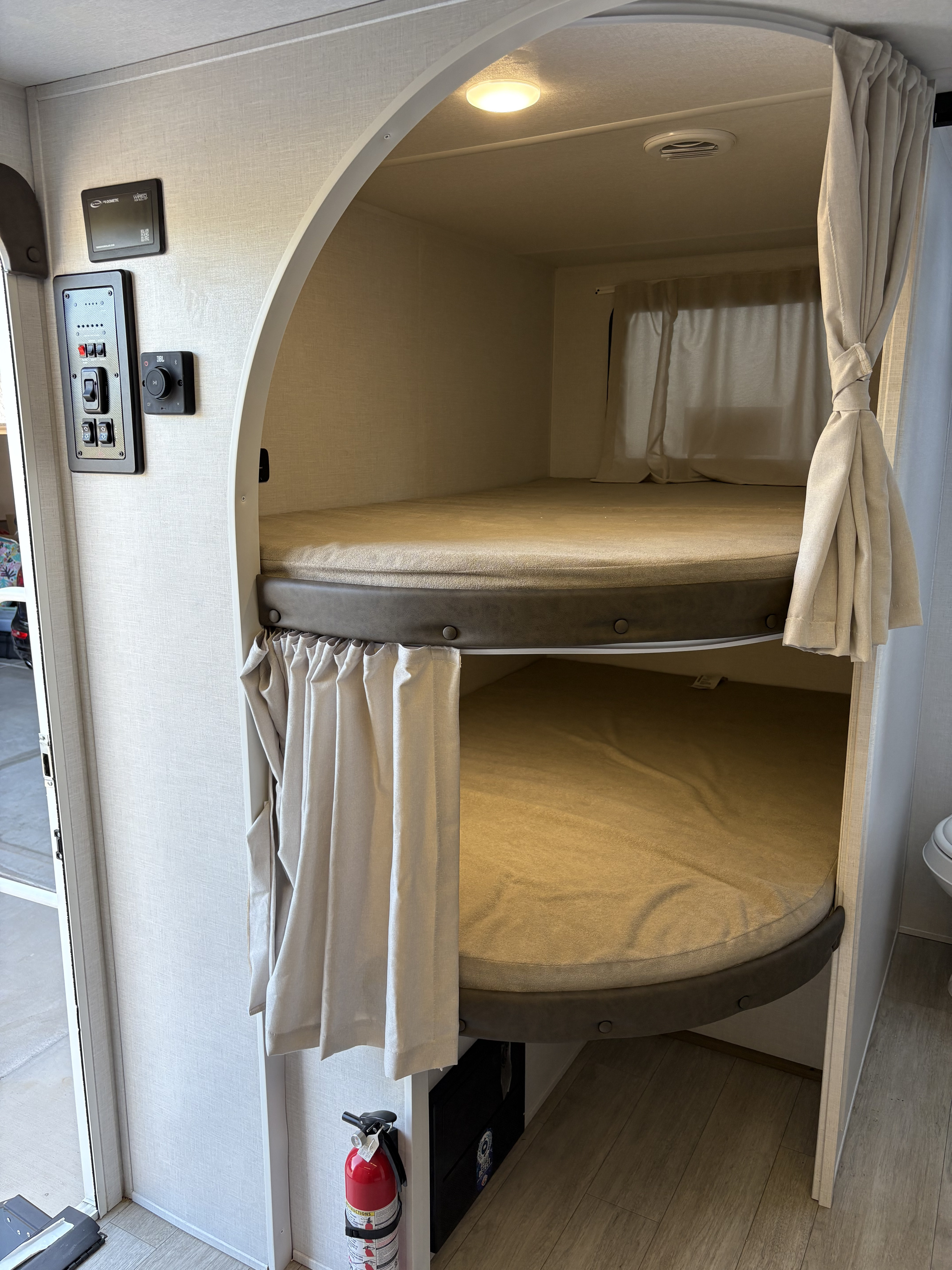 RV rental interior with stacked bunk beds in an arched alcove. Features privacy curtains, control panel, and ambient lighting.. Forest River Salem Cruise Lite 26ICE 2025