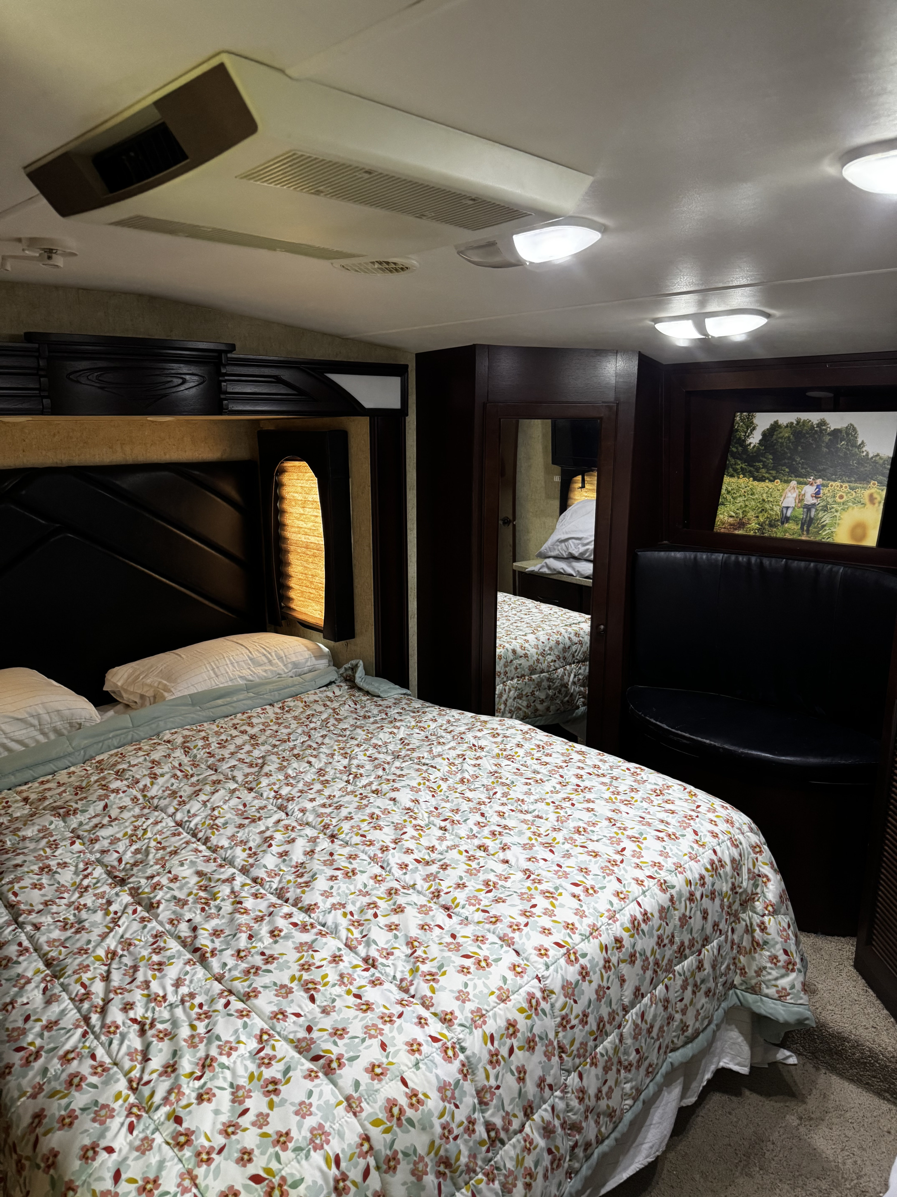 Comfortable RV bedroom with floral bedding, ceiling AC, and built-in seating, ideal for your next RV rental.. Heartland Cyclone 2013