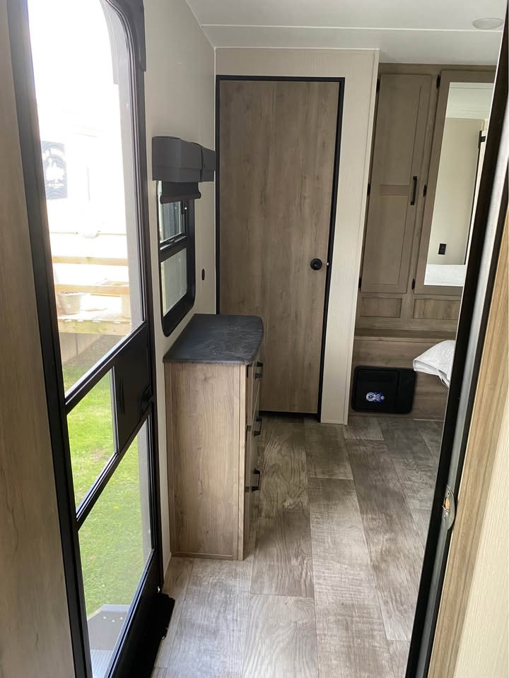 RV rental interior: View from the entrance showing wood-look flooring, storage, and bedroom area with a safe.. Forest River Palomino Puma 2024