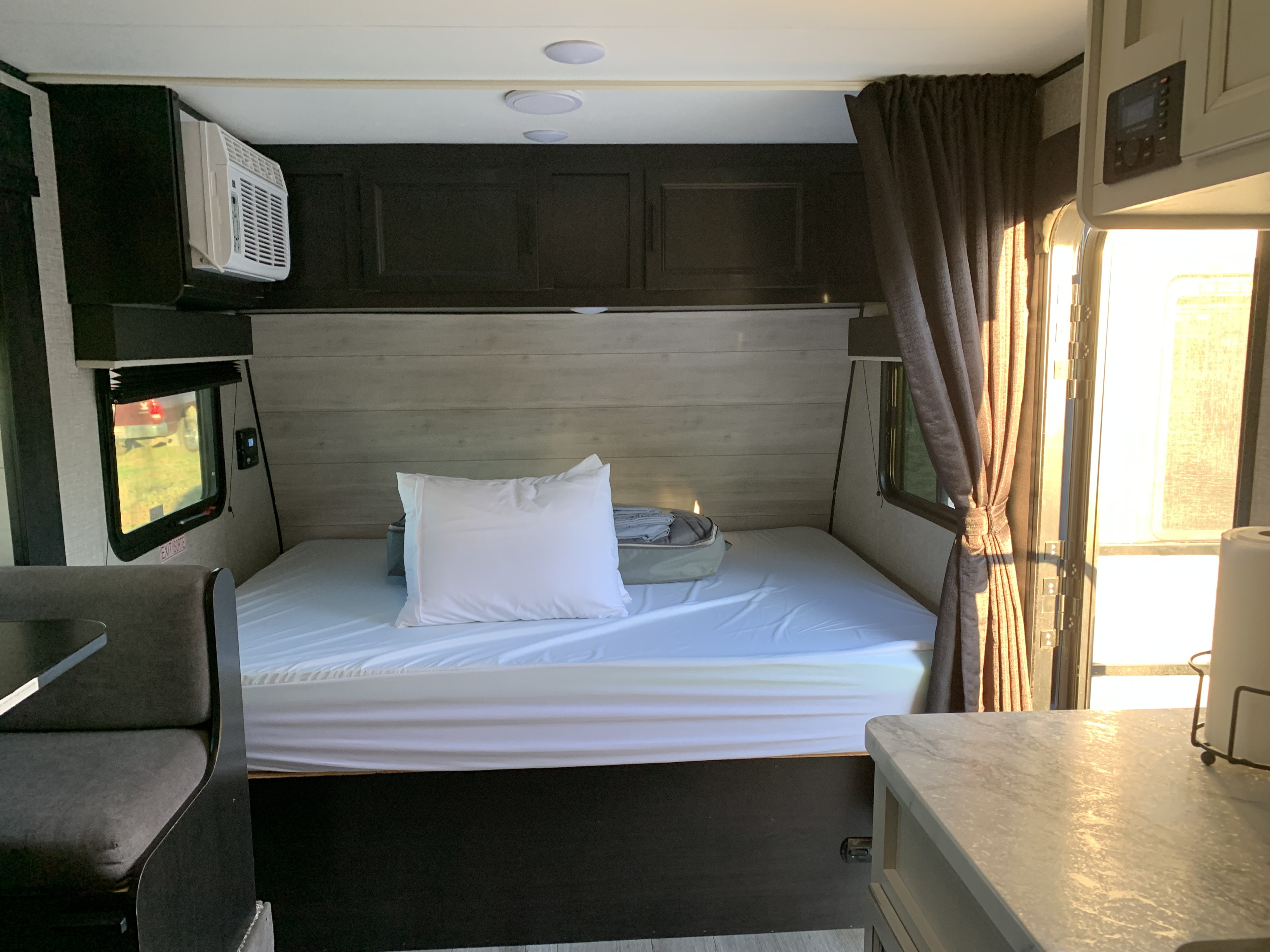 Inside an **RV rental**: A clean and functional interior featuring a bed, overhead storage, AC, and dinette area.. Jayco Jay Flight 2022