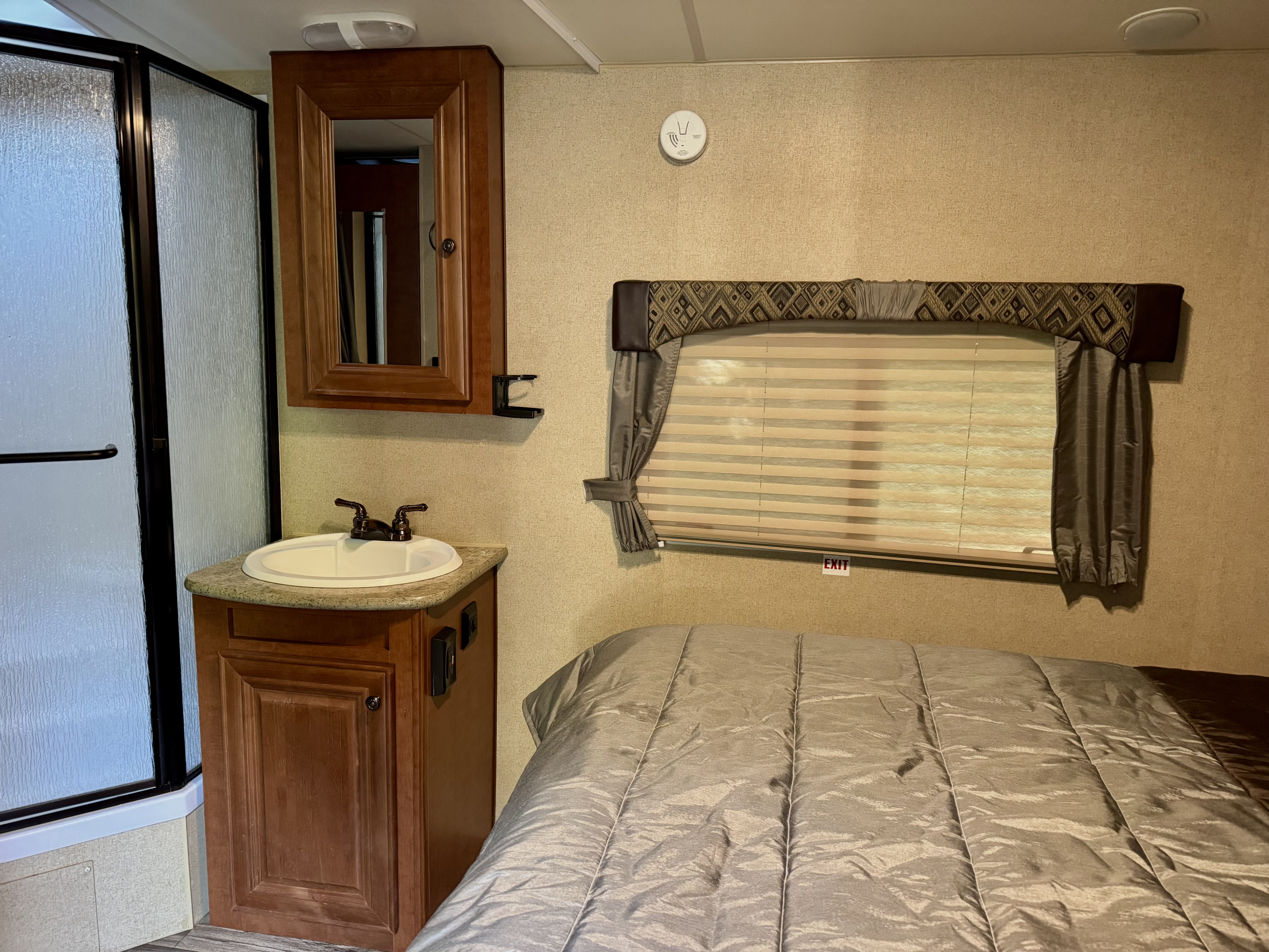RV rental interior showing a compact bedroom area with a comfy bed next to a small bathroom with shower and sink.. Arctic Fox Classic 2017