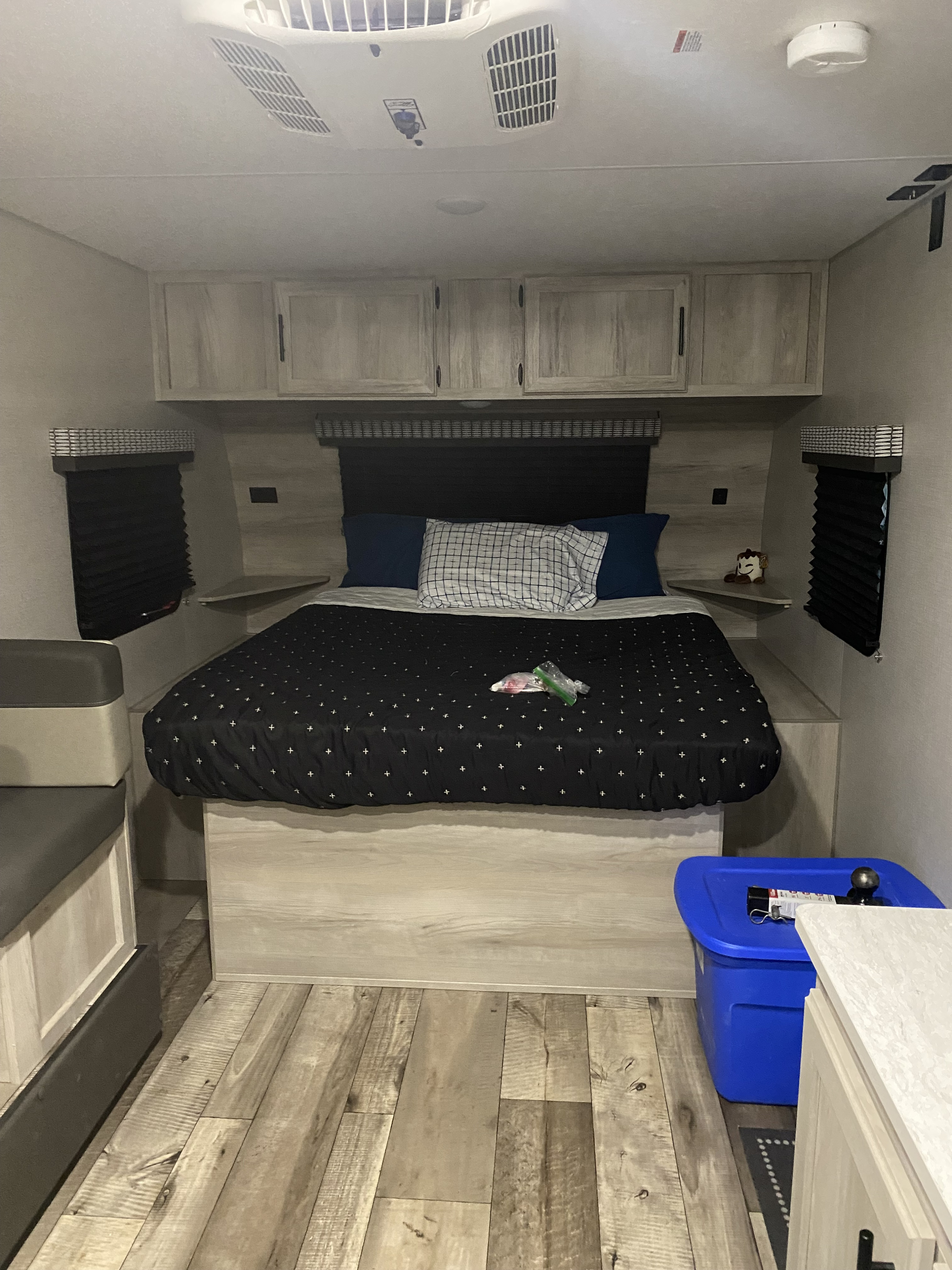 Inside an RV rental: a neat bedroom featuring a comfortable bed, built-in storage, and wood-style flooring.. Other Other 2021