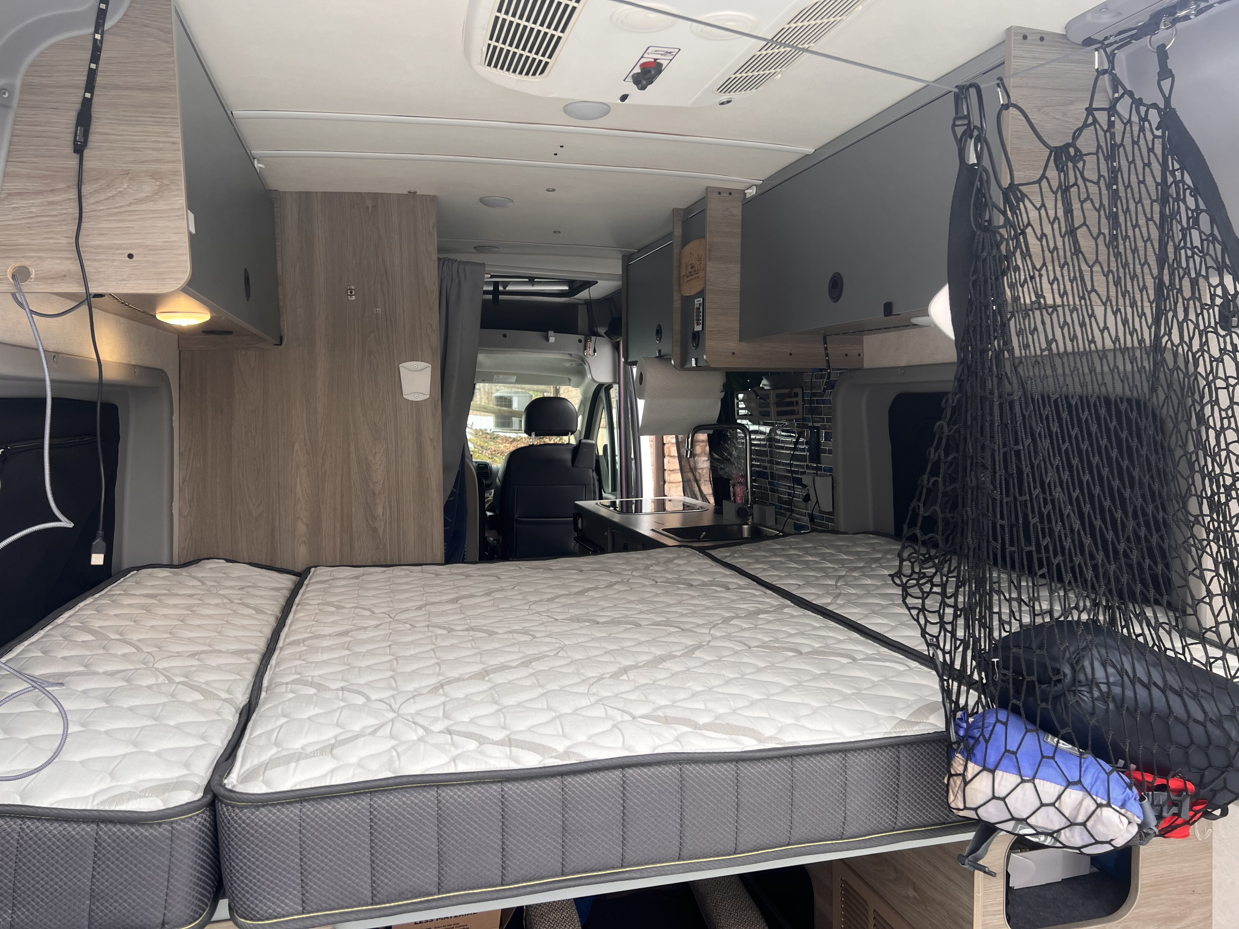 Cozy RV rental interior with bed, kitchenette, & overhead storage for comfortable travels.. Winnebago Solis 2023