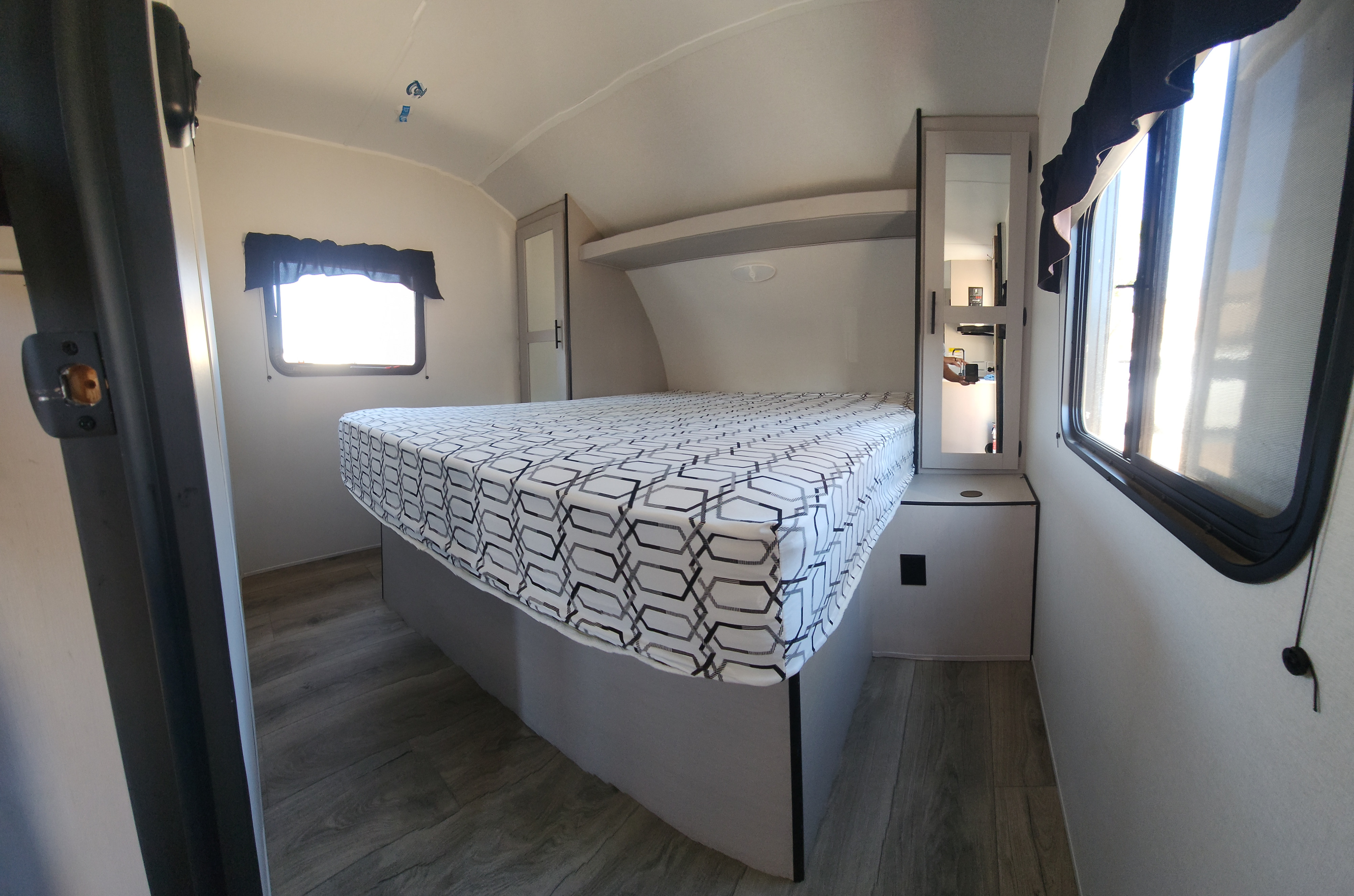 Spacious RV rental bedroom with a comfortable bed, mirrored cabinet, and large windows, ready for your next journey.. Heartland RVs Prowler 2024