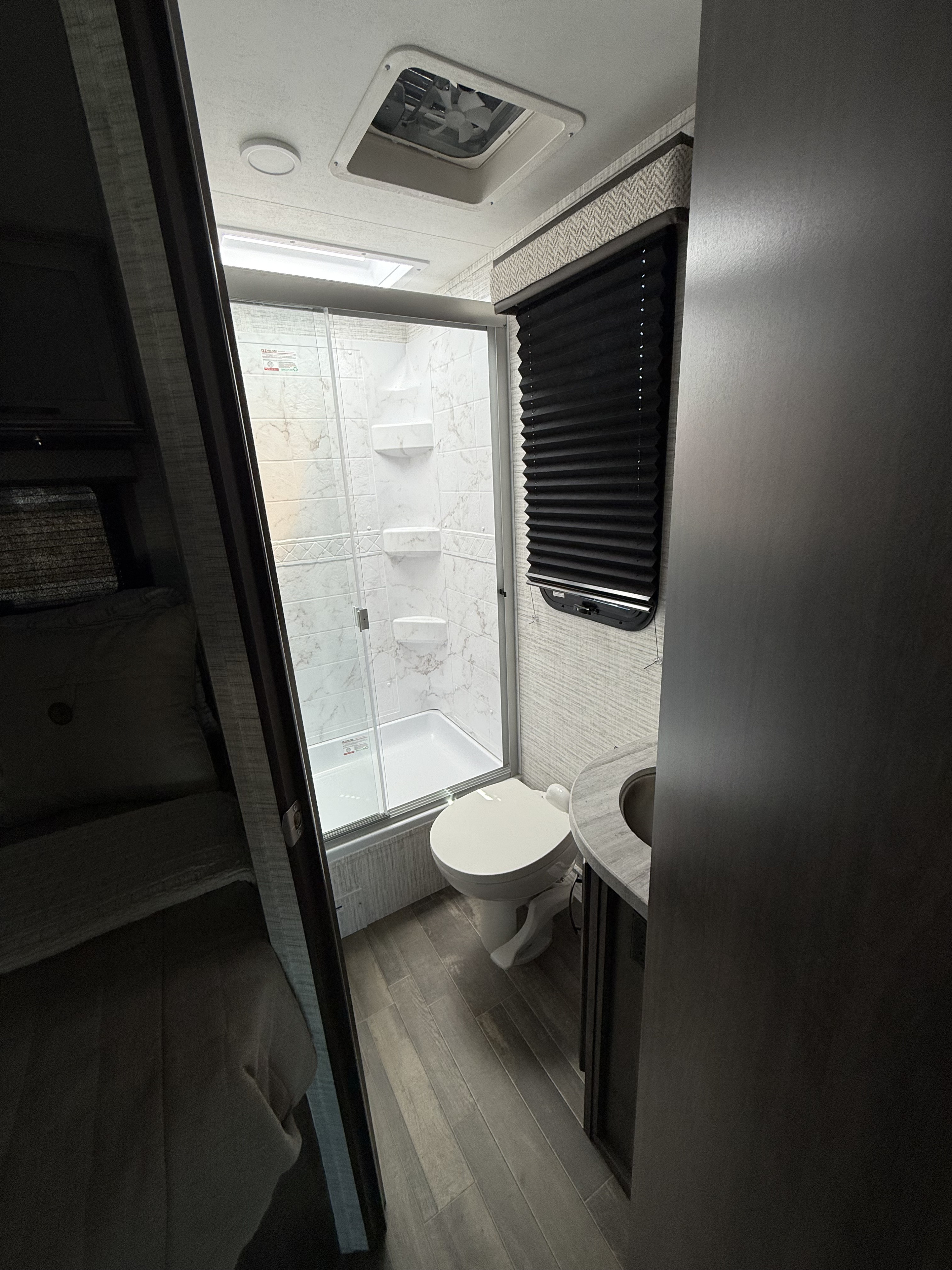 Compact and modern RV rental bathroom with shower, toilet, and vanity. Enjoy essential amenities for your road trip comfort.. Entegra Odyssey 2025