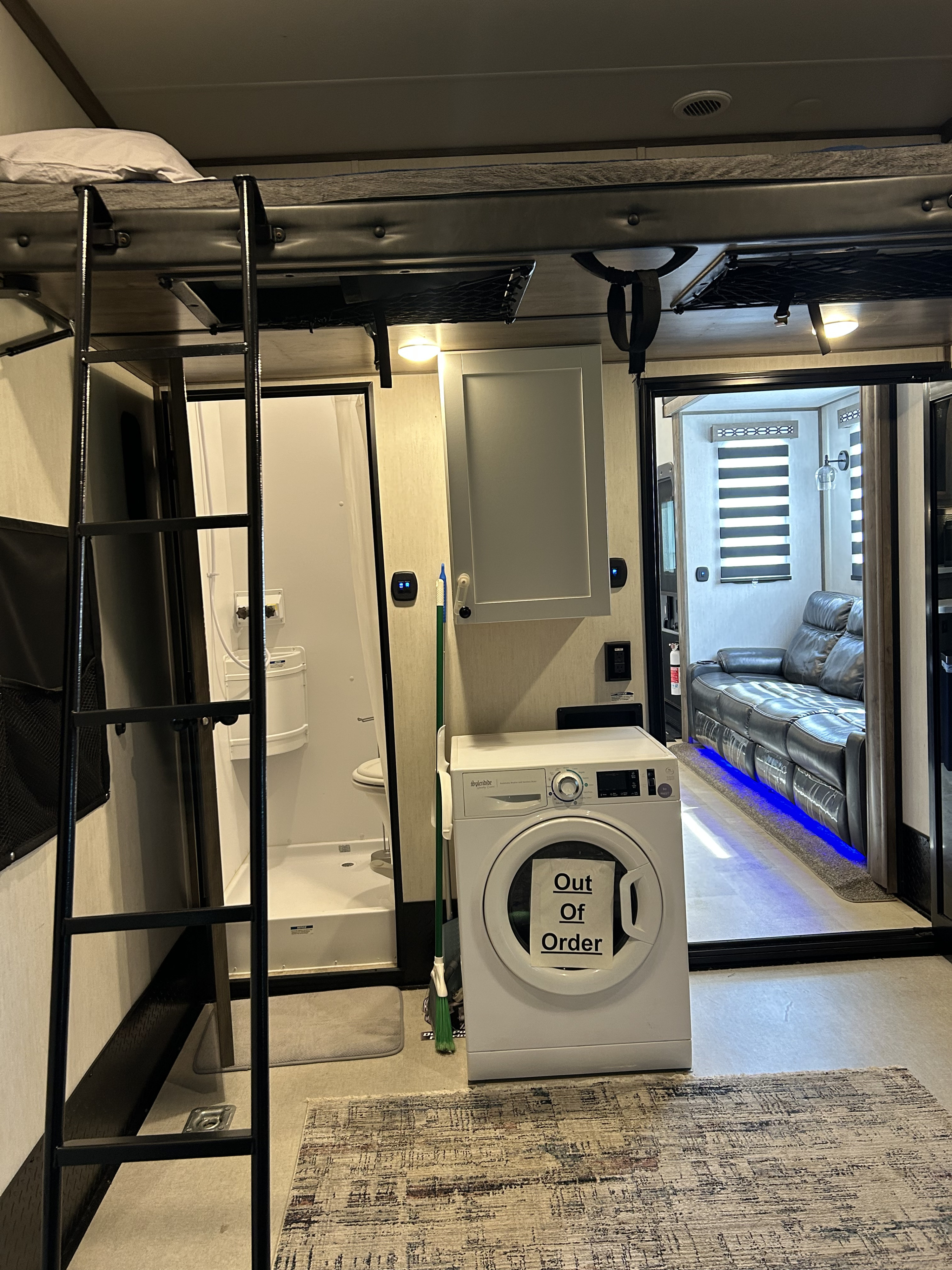 RV rental interior: A bunk bed, compact bathroom, and a washer (out of order) near a living area with a comfy couch.. Forest River Vengeance Vengeance Rogue Toy Hauler 2022